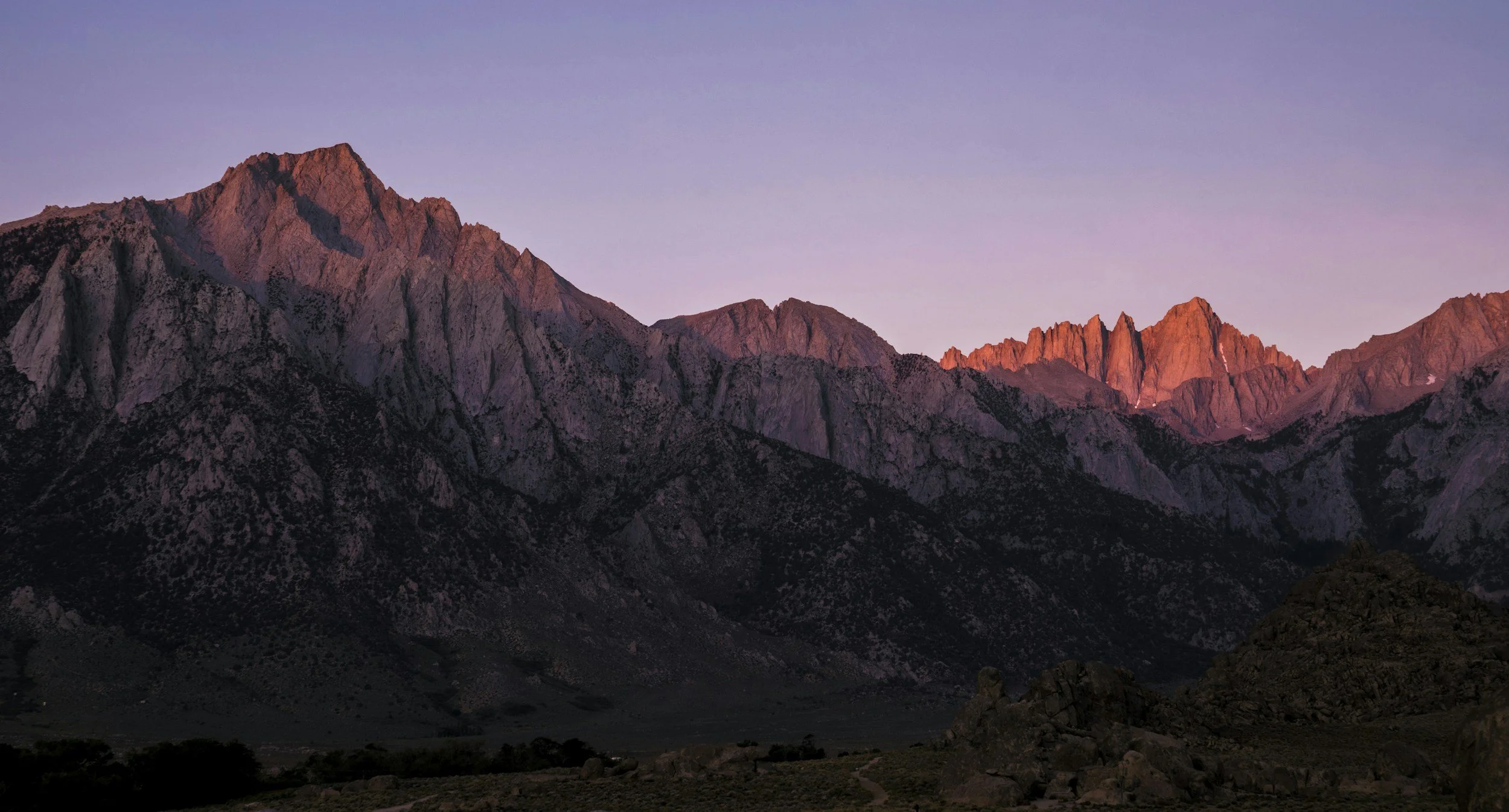 Mountain range during sunset with pink and purple hues in the sky.