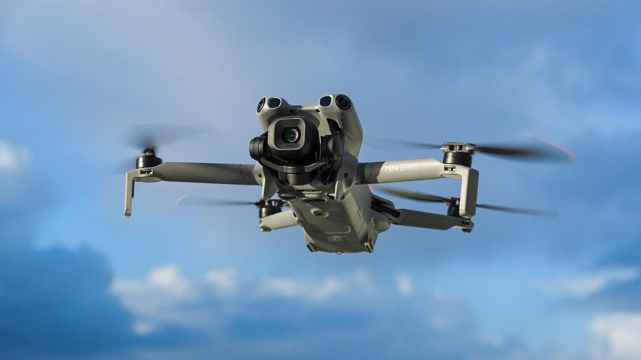 Un drone quadricoptère en vol dans le ciel bleu avec quelques nuages