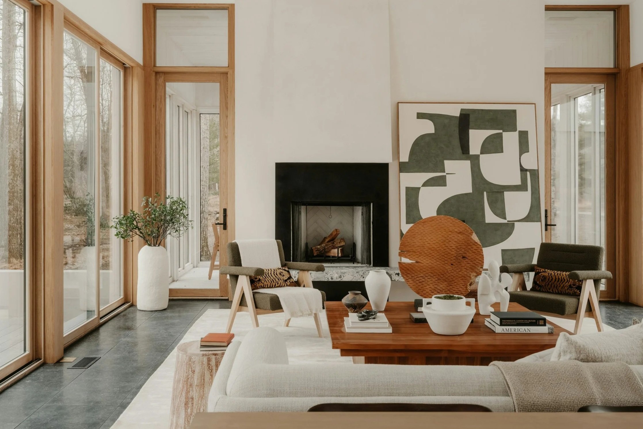 Living room with large windows, a fireplace, abstract wall art, and modern furniture.