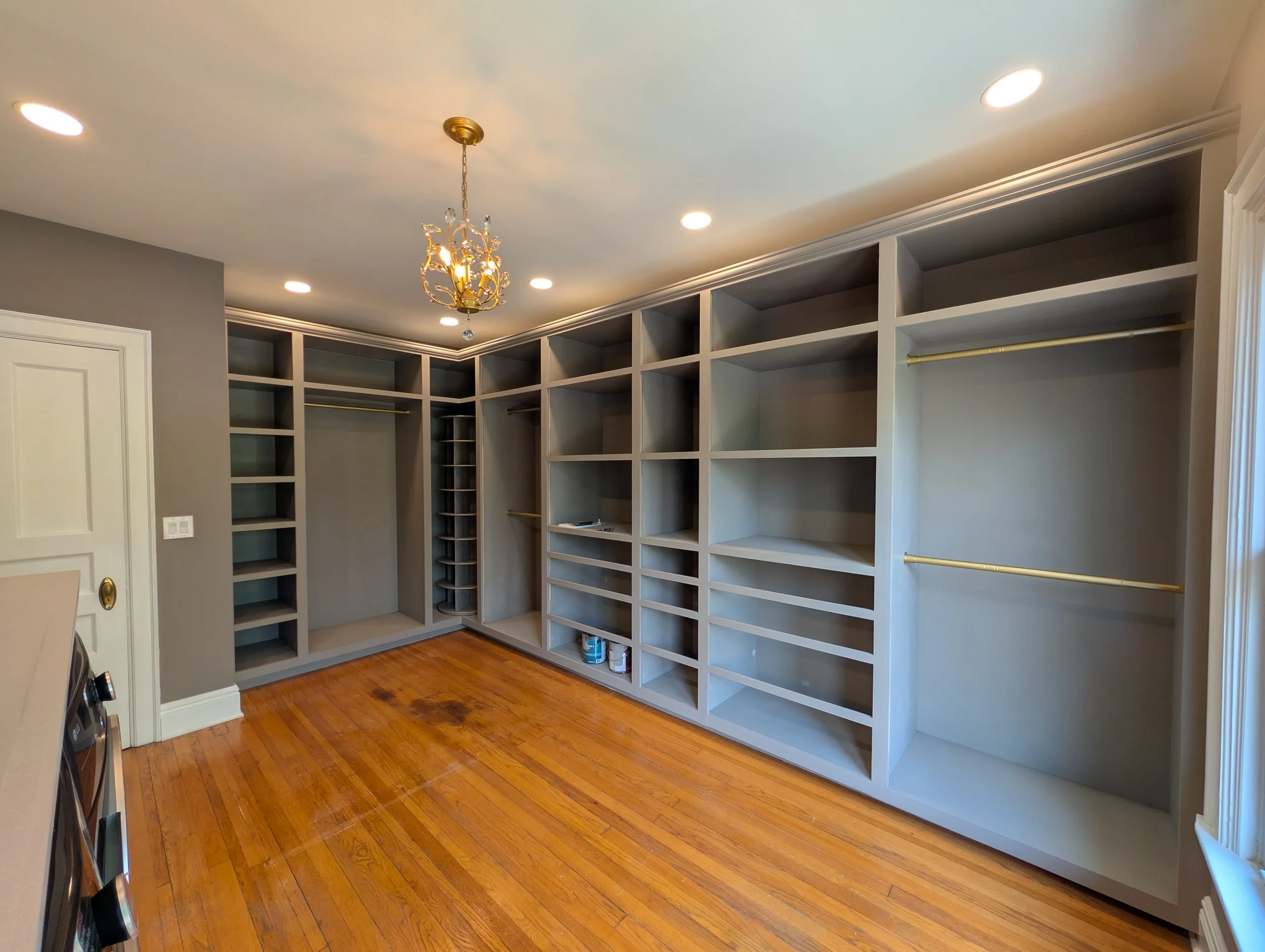 Empty walk-in closet with built-in shelves, hanging rods, and hardwood flooring.