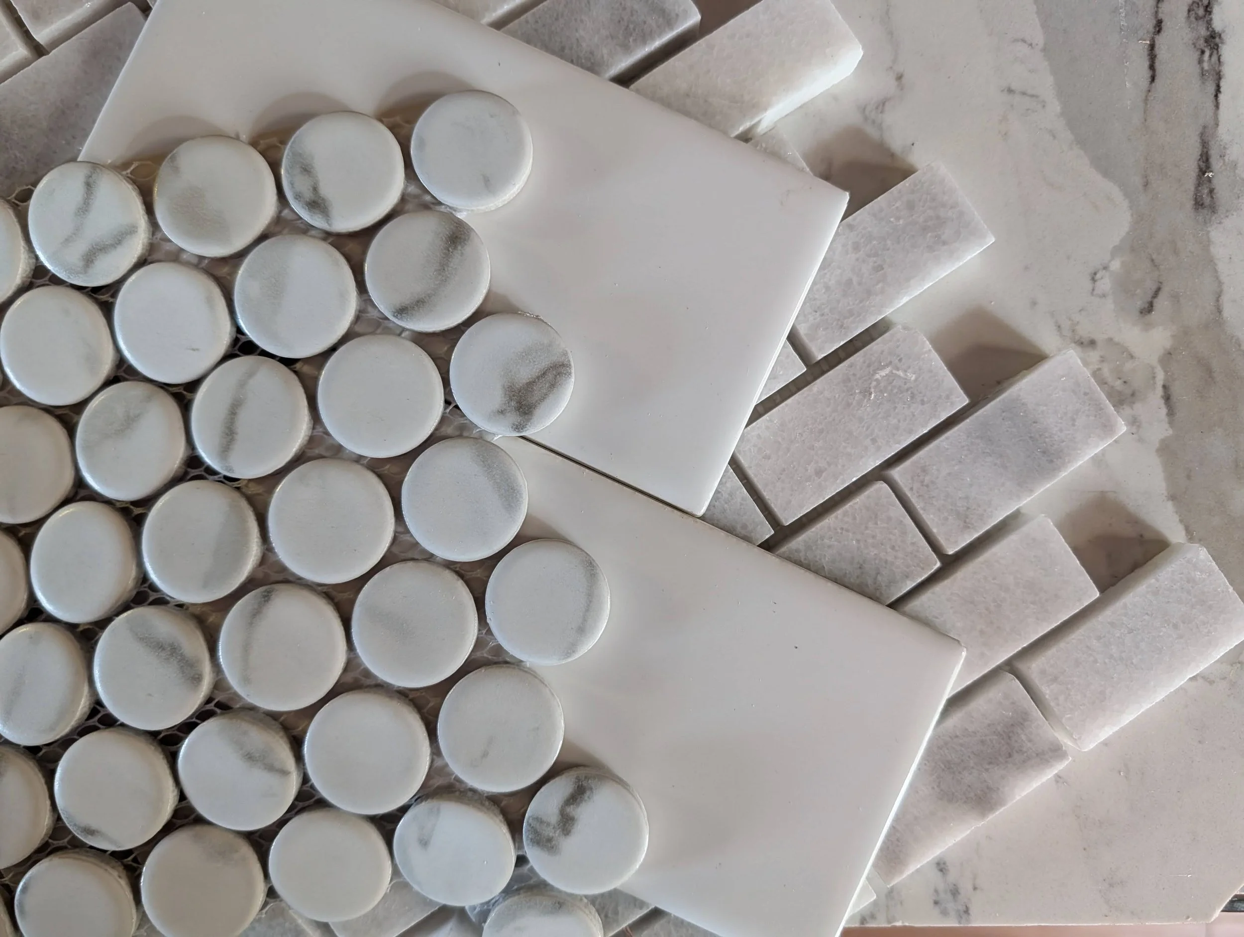 Close-up of white tiles, some with a frosted glass appearance, arranged in rows on a tiled surface.