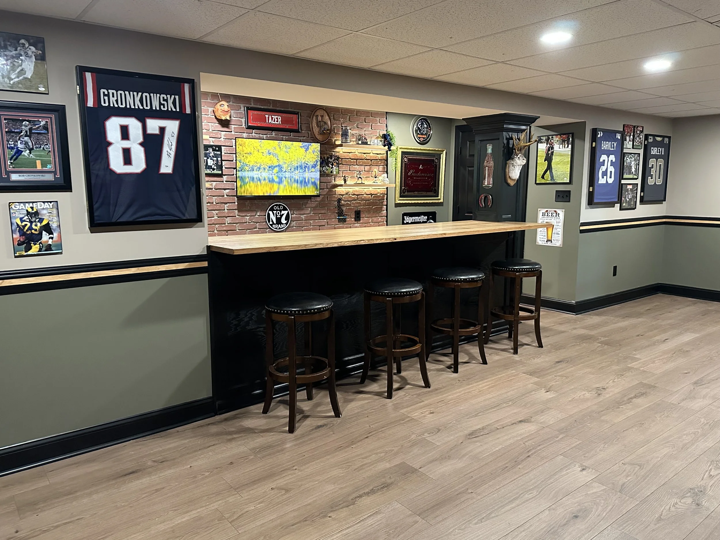 After- Custom basement bar with custom cabinetry, oak wood countertop, brick accent wall, built-in shelving, and LED lighting