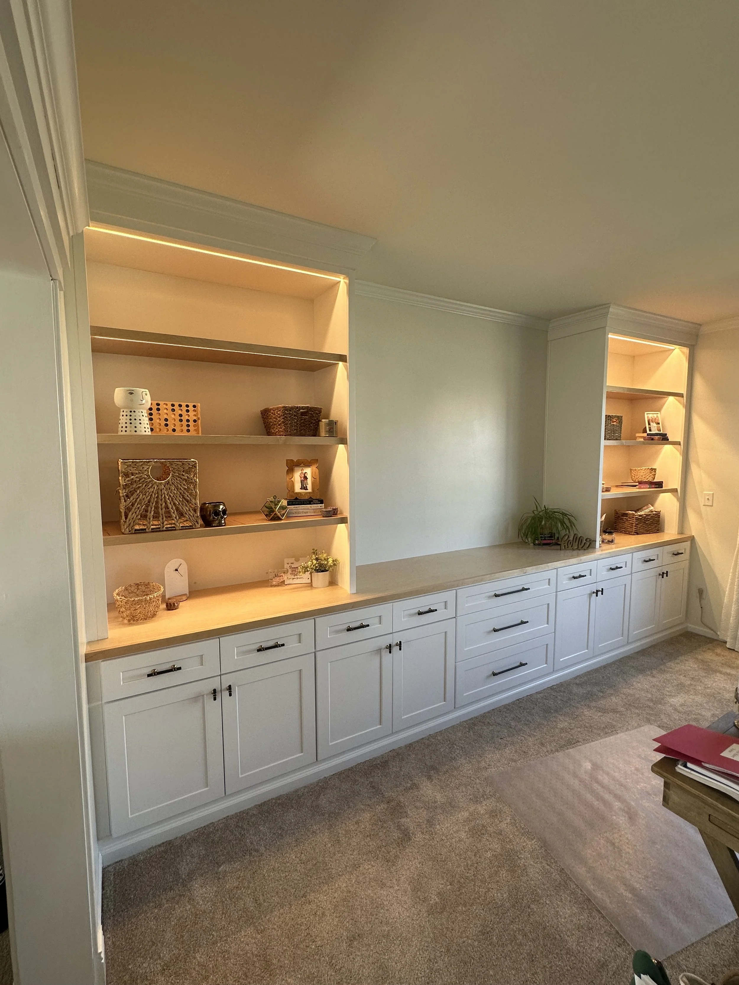 Custom built in for home office with white cabinets, open shelving, and LED lighting.