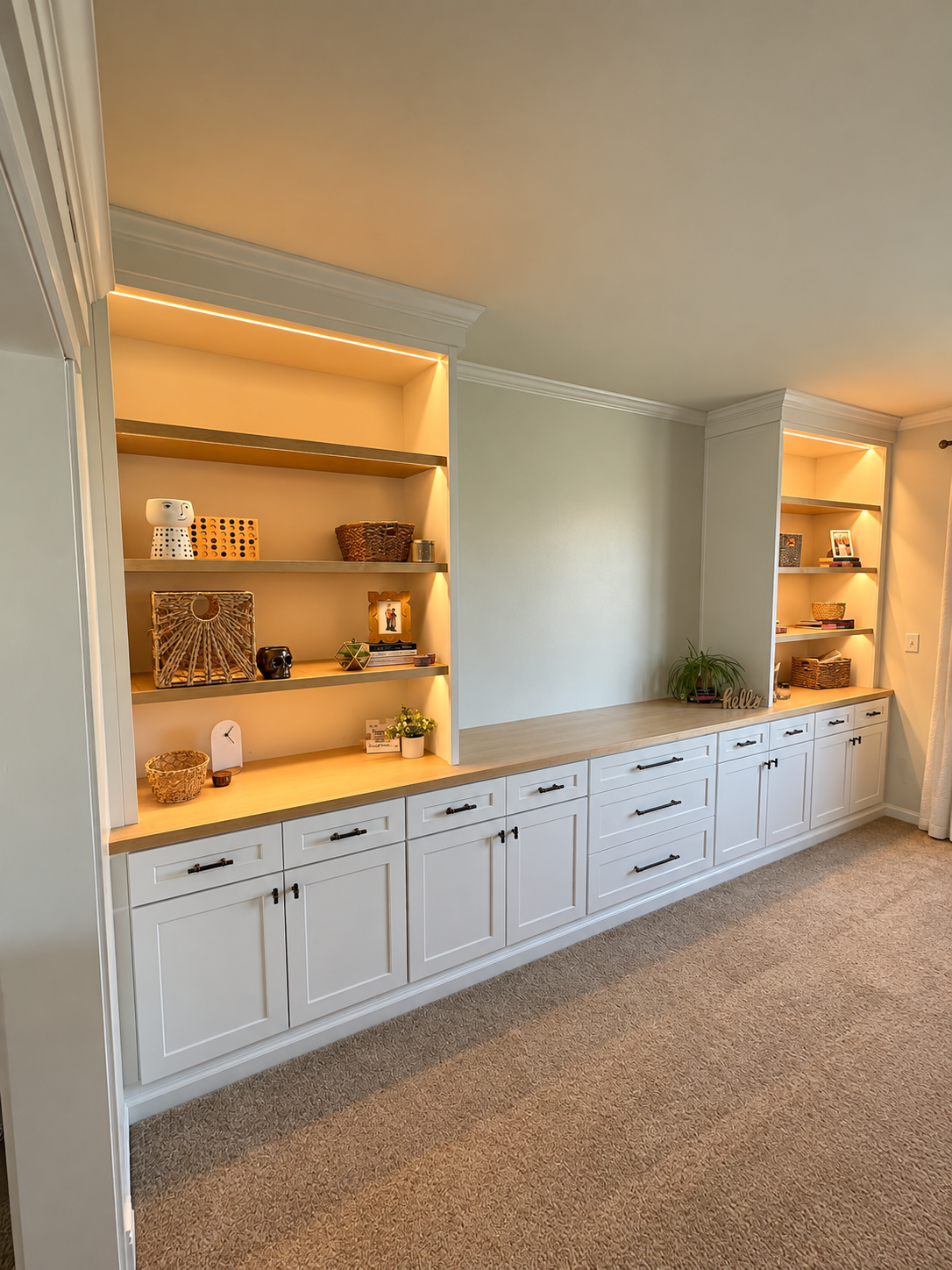Built-in white cabinets with open shelves illuminated by warm LED lighting and finished with crown molding.