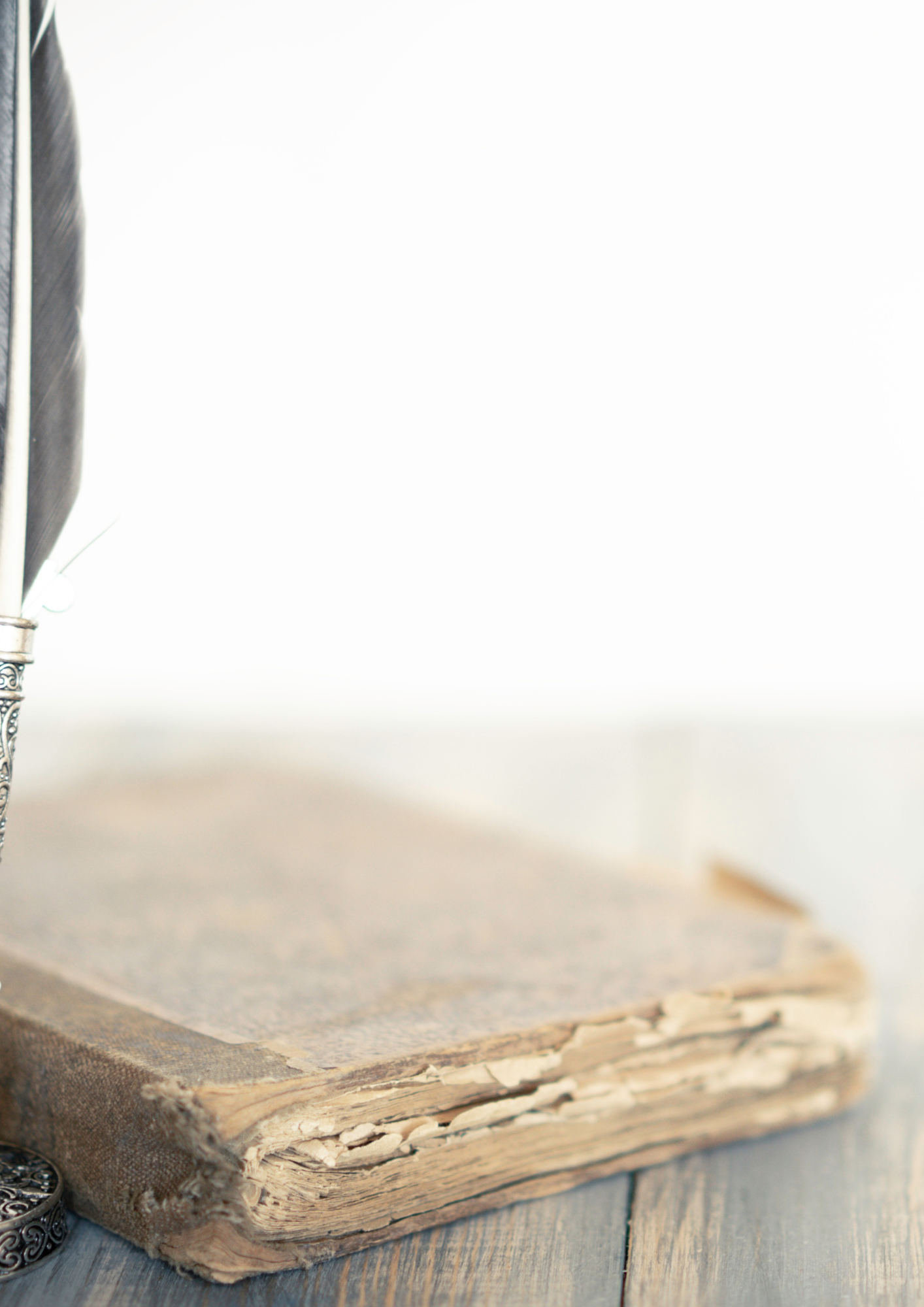 Ein alter, aufgebockter, beschädigter Buchstapel mit abgenutzter Seite auf einem Holztisch.