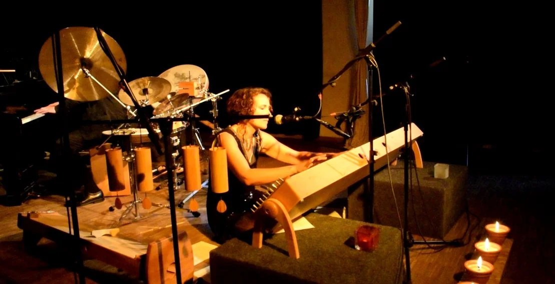 Soul Spa Berlin Live Theta Traumreise –Musikerin spielt Keyboard bei einem Musikauftritt, mit Kerzen auf dem Boden im Vordergrund und einem Schlagzeug im Hintergrund.