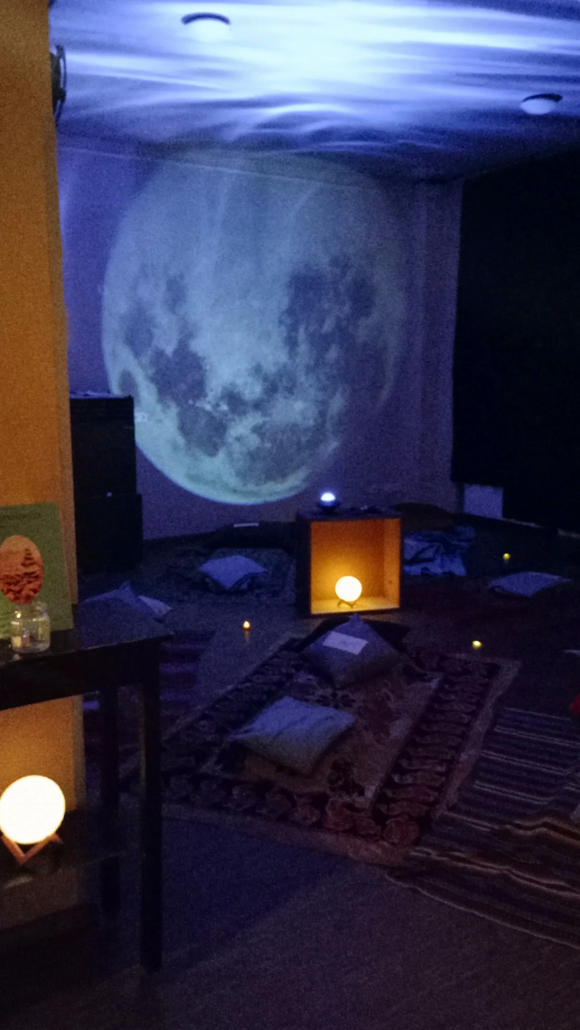 Atmosphärischer Raum mit Mondprojektion und Meditationskissen für die exklusiven Live Theta Traumreisen Events des Soul Spa Berlin.