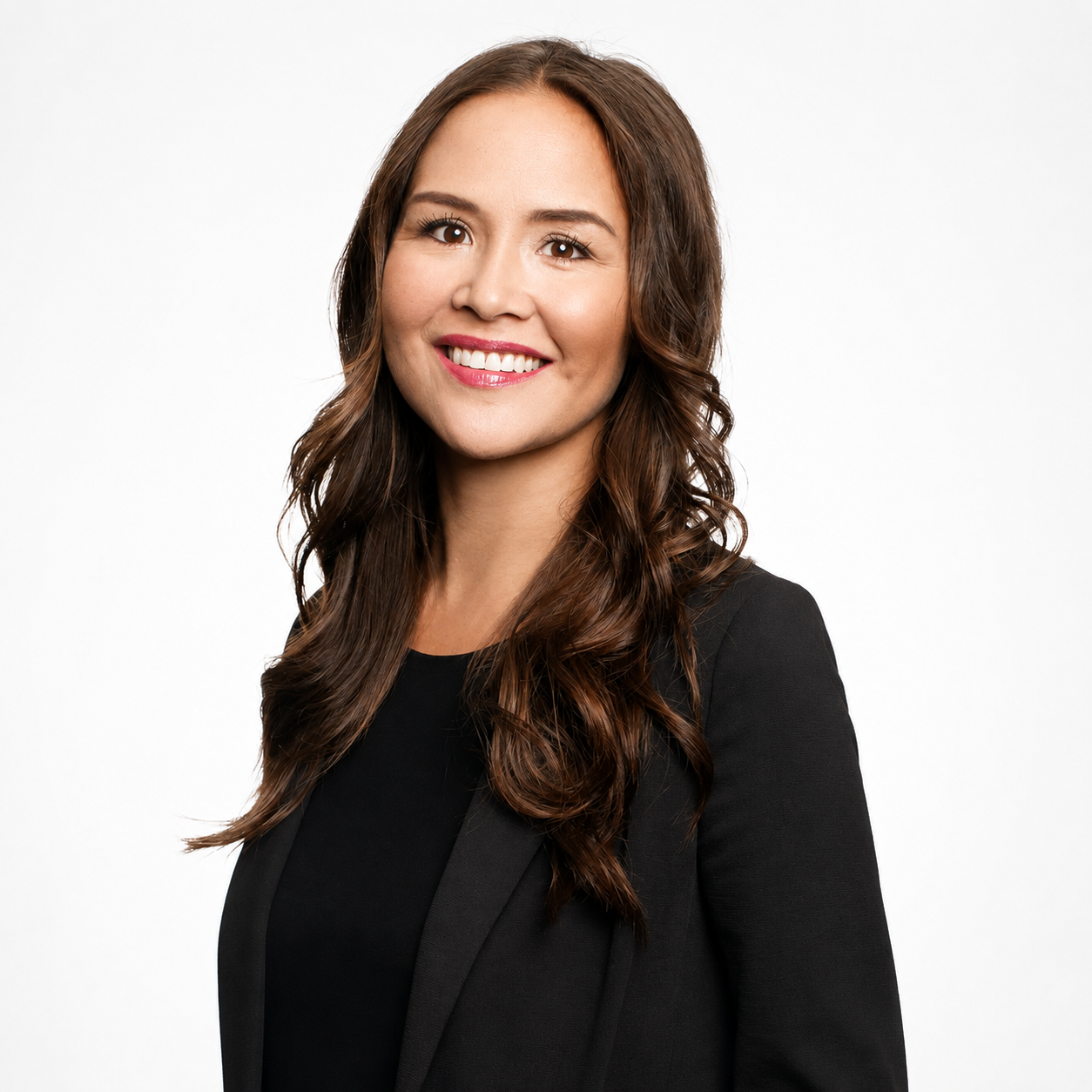A woman with long brown hair smiling, wearing a black blazer and top, positioned against a plain white background.