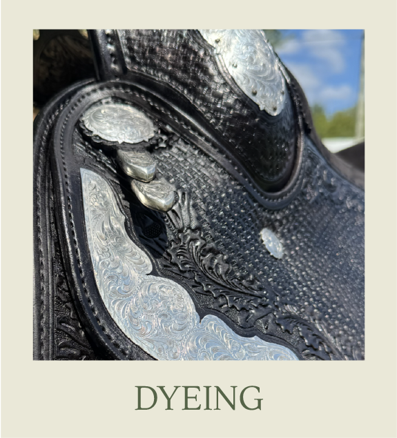 Close-up of a black leather cowboy boot with detailed silver tooling and western design, showing scuffed and worn areas.