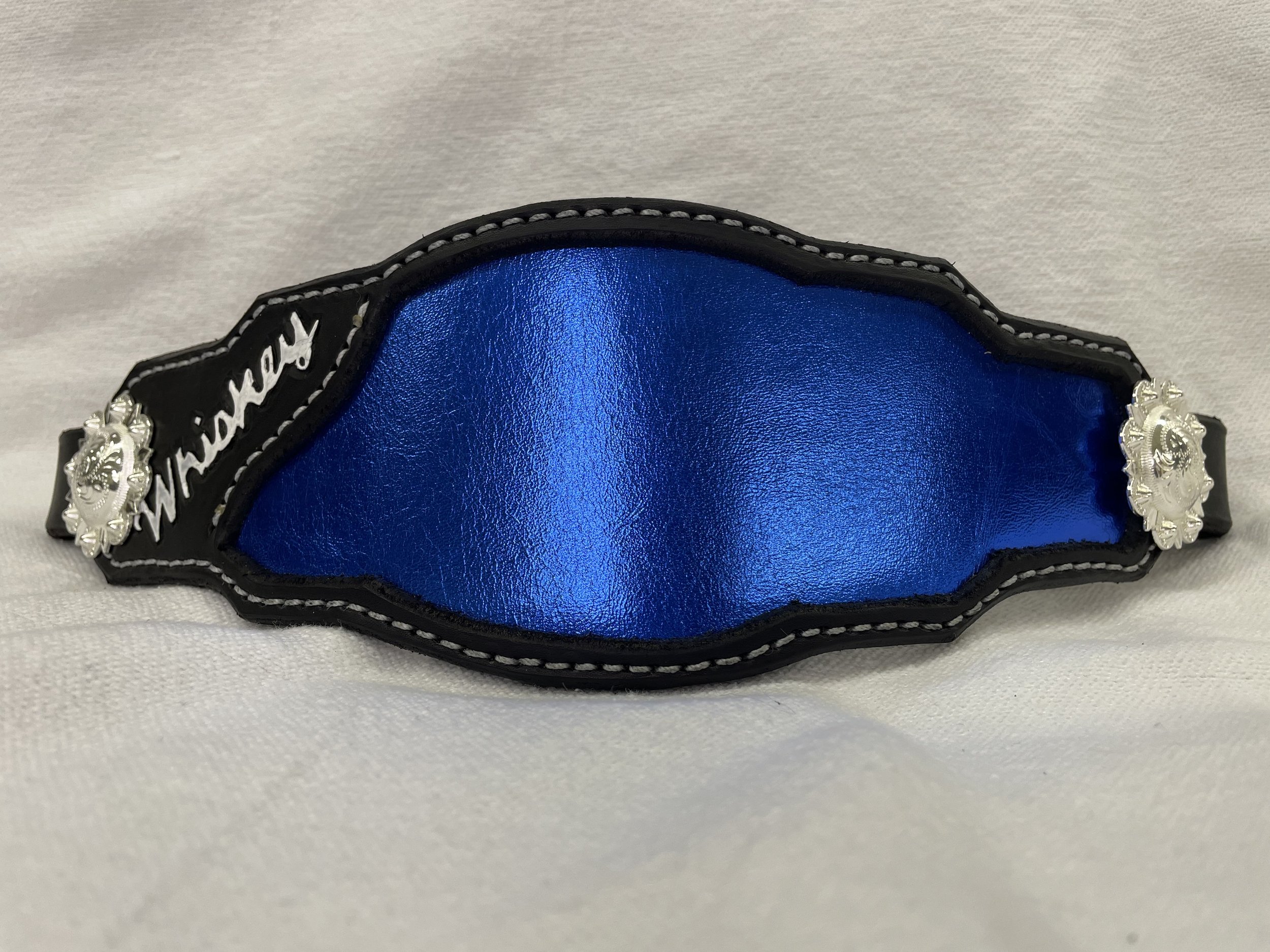 A close-up view of blue and black leather accessory with white stitching and silver decorative elements.