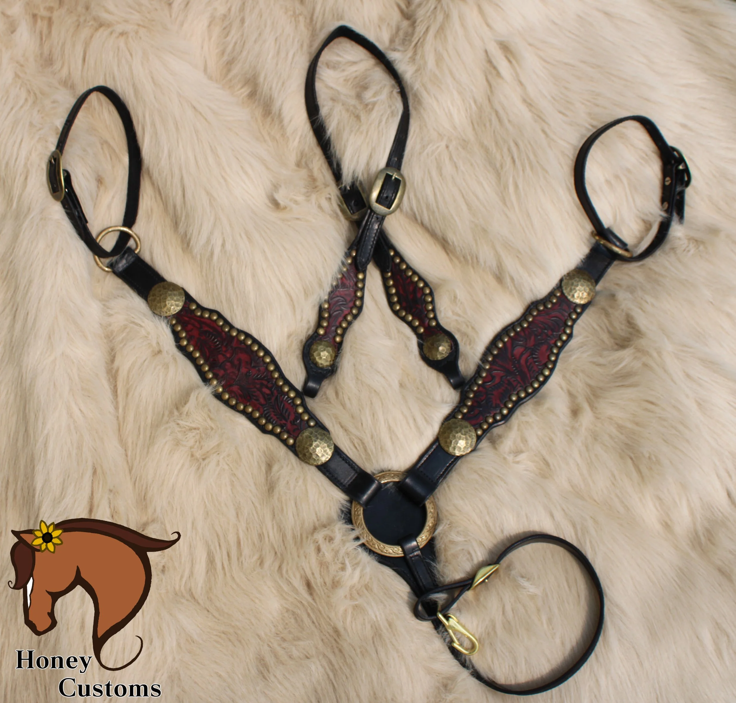 Three black leather collars with metal buckles and decorative elements laid out on a cream fur surface.