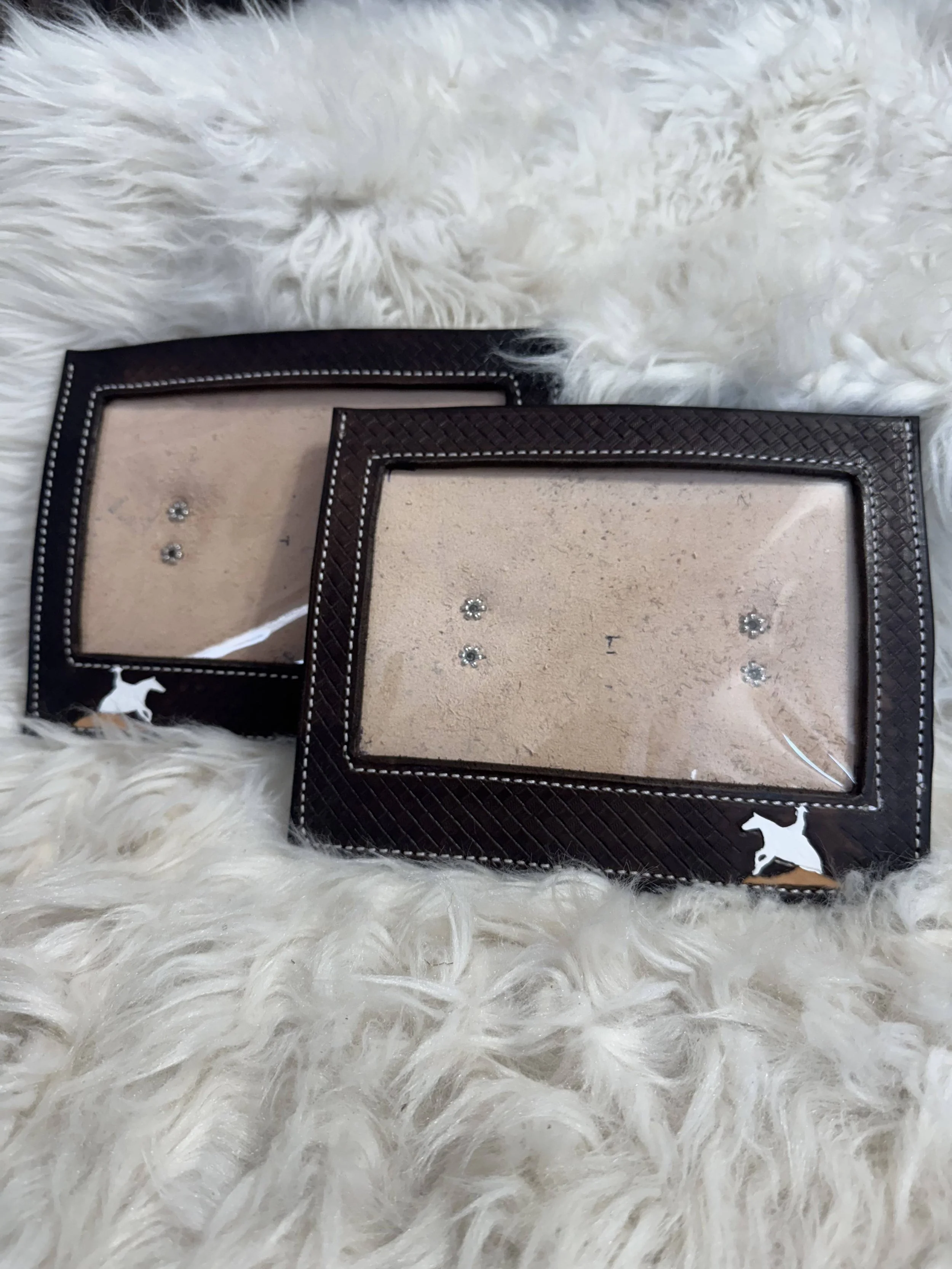 Two picture frames with mirrored glass and dark brown textured borders, placed on a fluffy white fur surface.