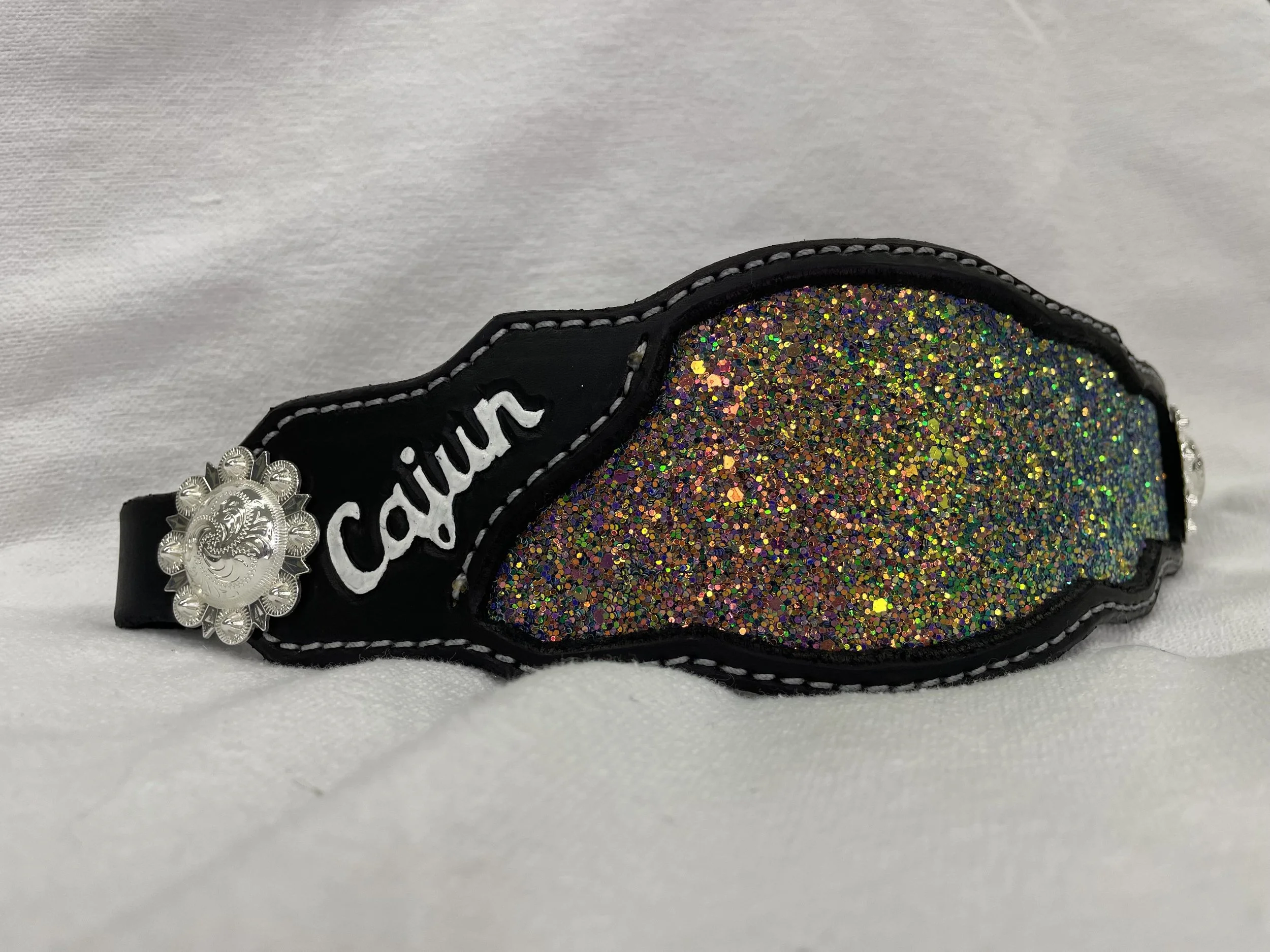 Close-up of a black shoe with multicolored glitter design on the side and silver embellishments.