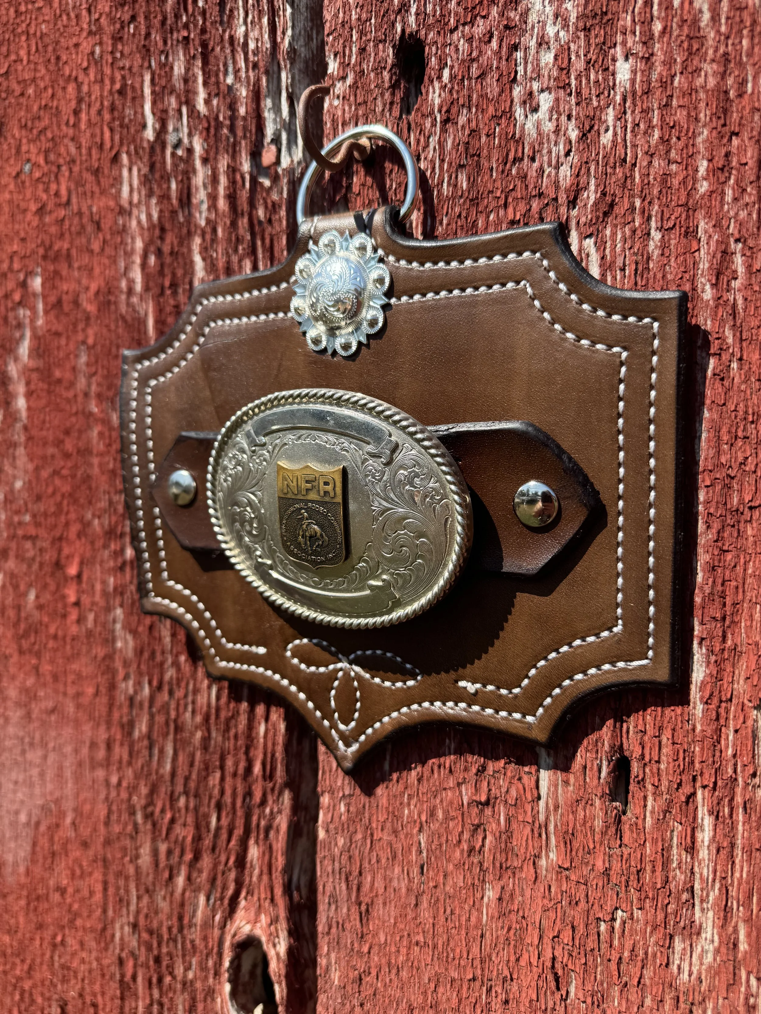 Close-up of a Sheriff's badge hanging on a red, weathered wooden wall.