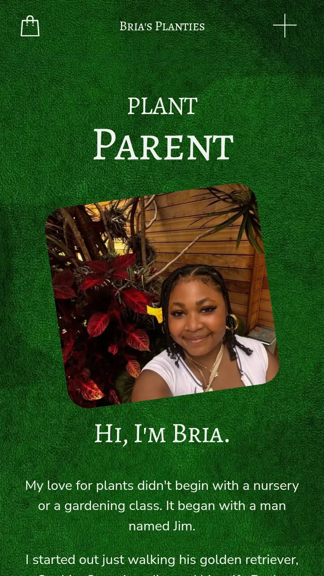 A woman smiling, taking a selfie in front of indoor red and green plants, with a wooden wall in the background.