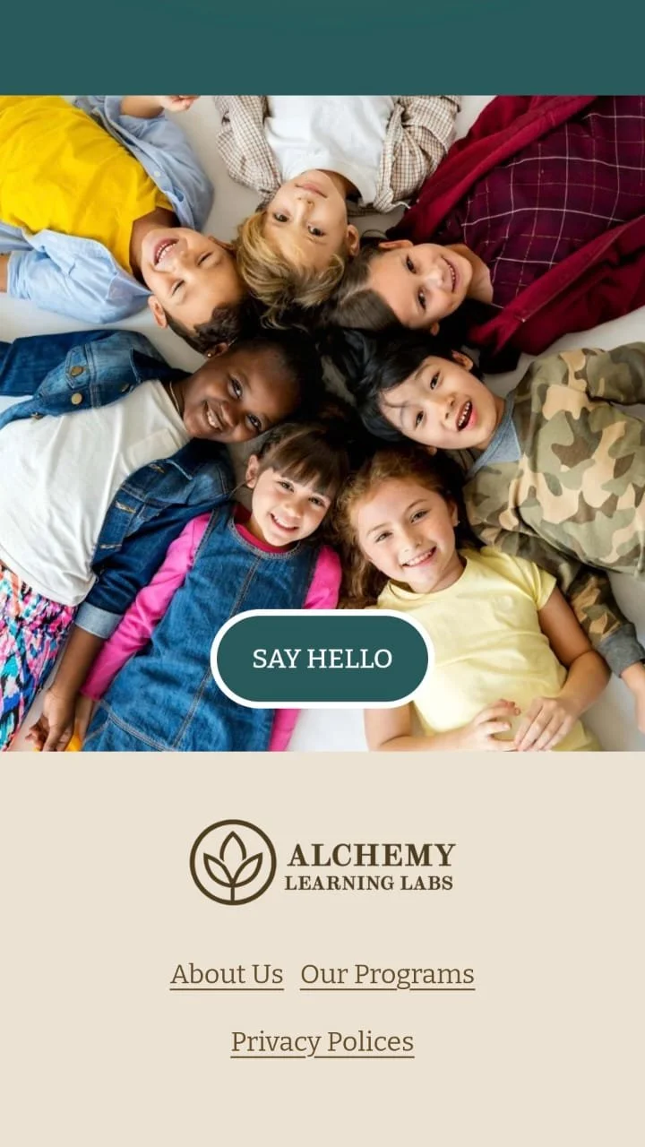A group of children lying in a circle on the floor, smiling and looking up at the camera. There are seven kids, wearing colorful and casual clothing.