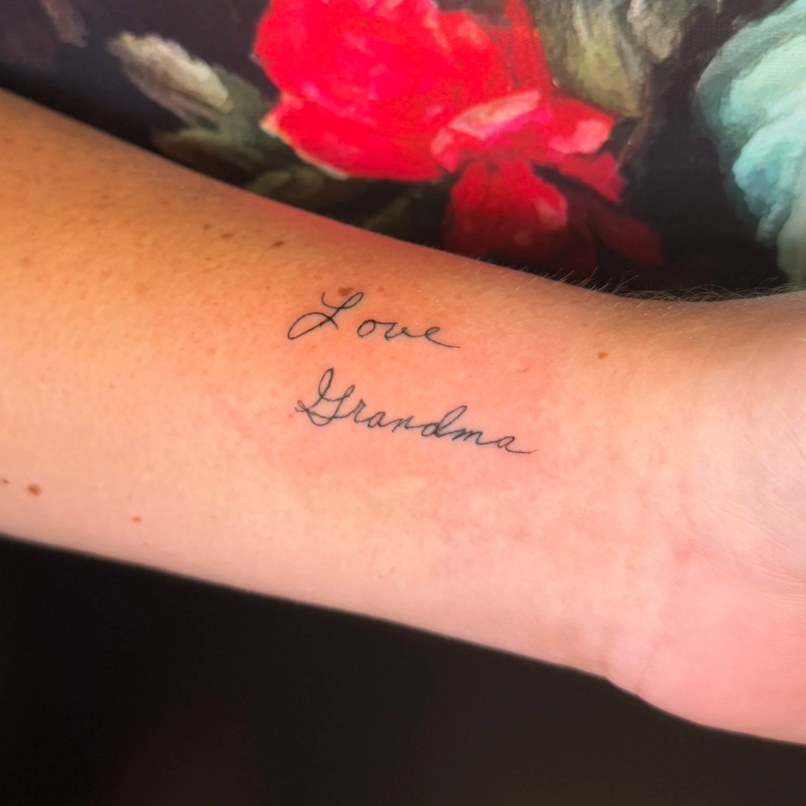 A tattoo on a person's inner arm with the words 'Love Grandma' written in cursive black ink.