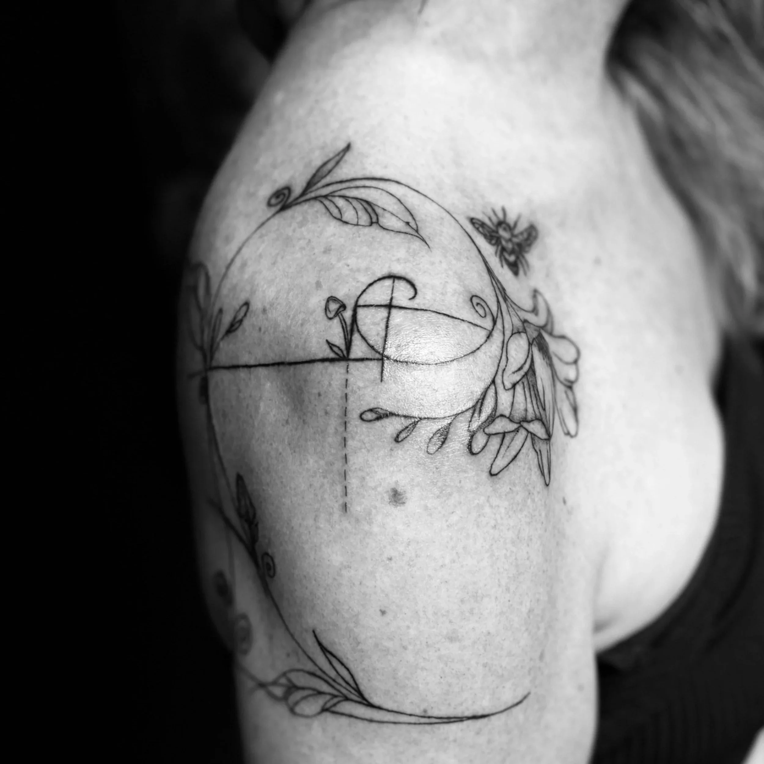 Close-up of a tattoo on skin featuring a butterfly and floral design in black ink.