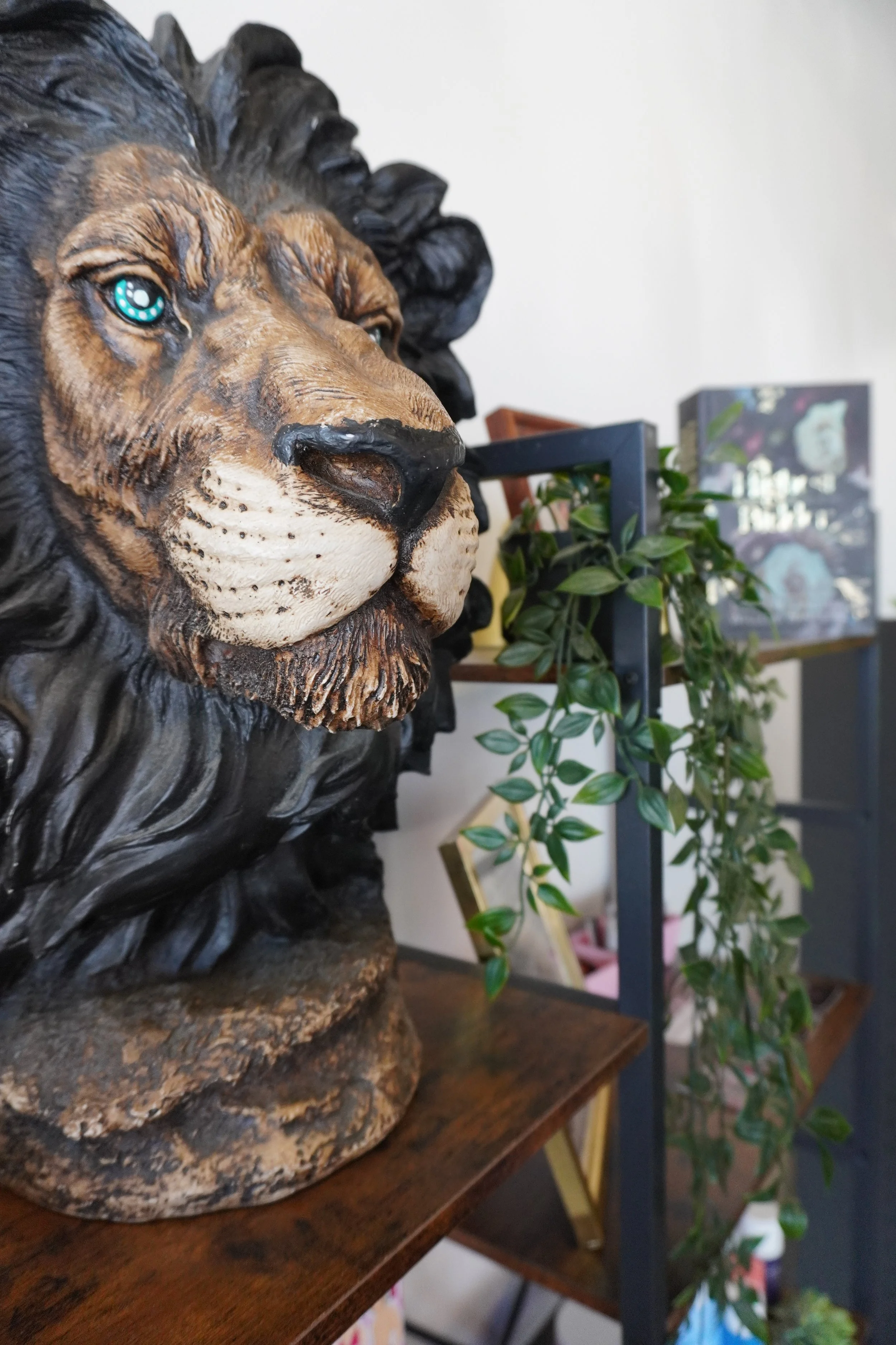 Close-up of a decorative lion bust with detailed facial features and a flowing mane, mounted on a wooden surface.