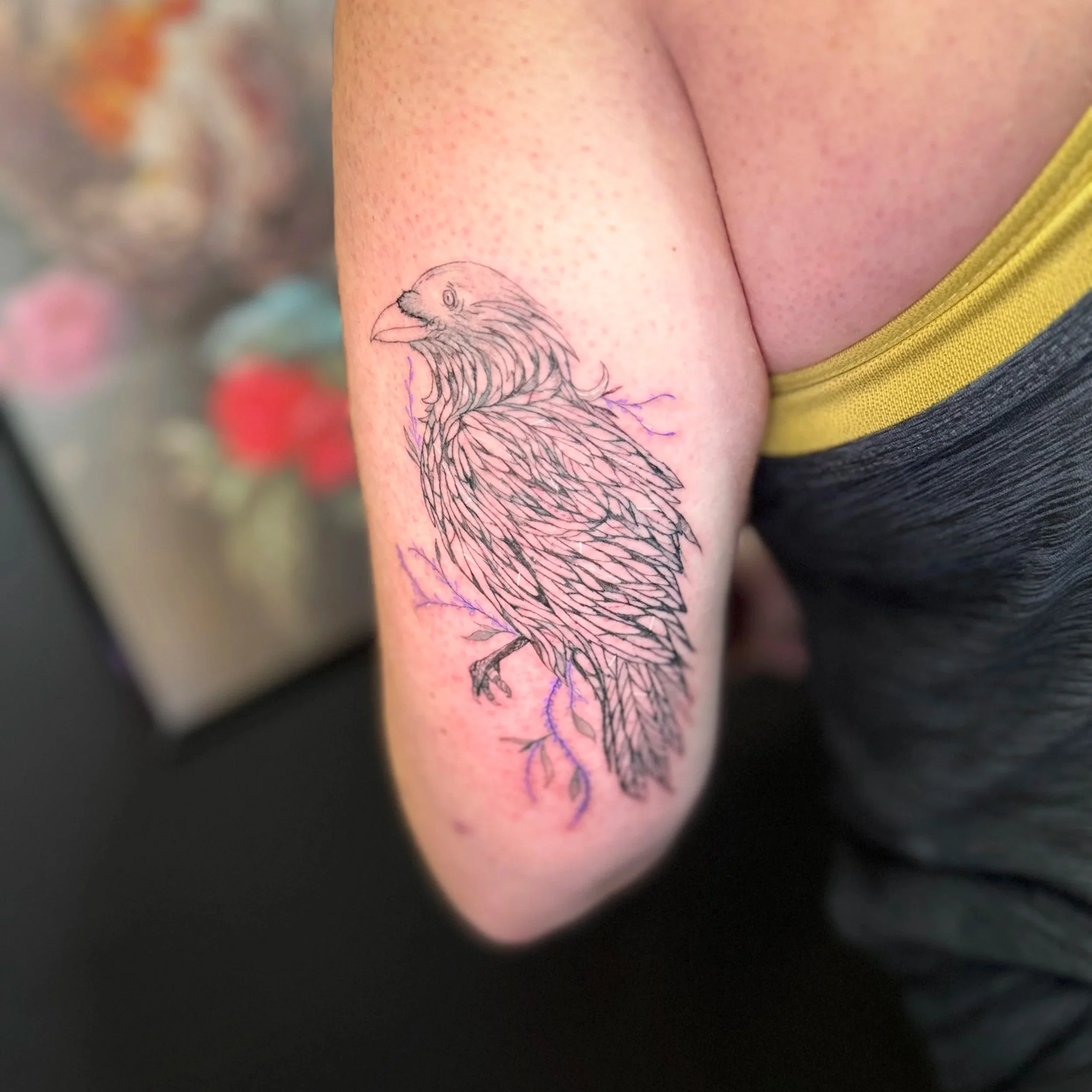 A tattoo of a bird with a long beak and detailed feathers on a person's upper arm.