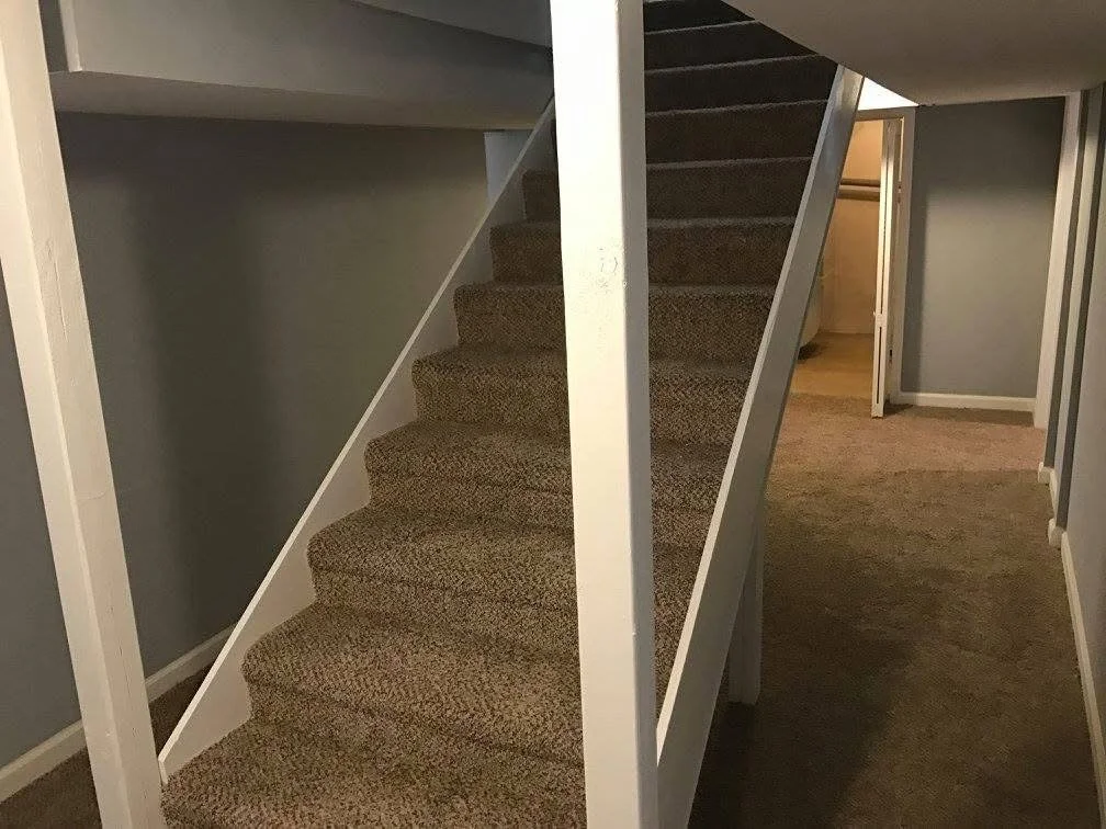 Indoor staircase with brown carpet leading to an upper floor, with hallway and doors visible.