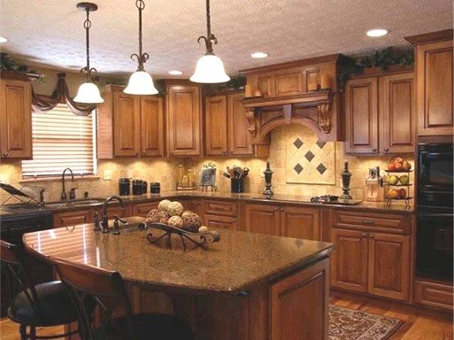 Kitchen with wooden cabinets, granite island, hanging lights, and window with blinds.