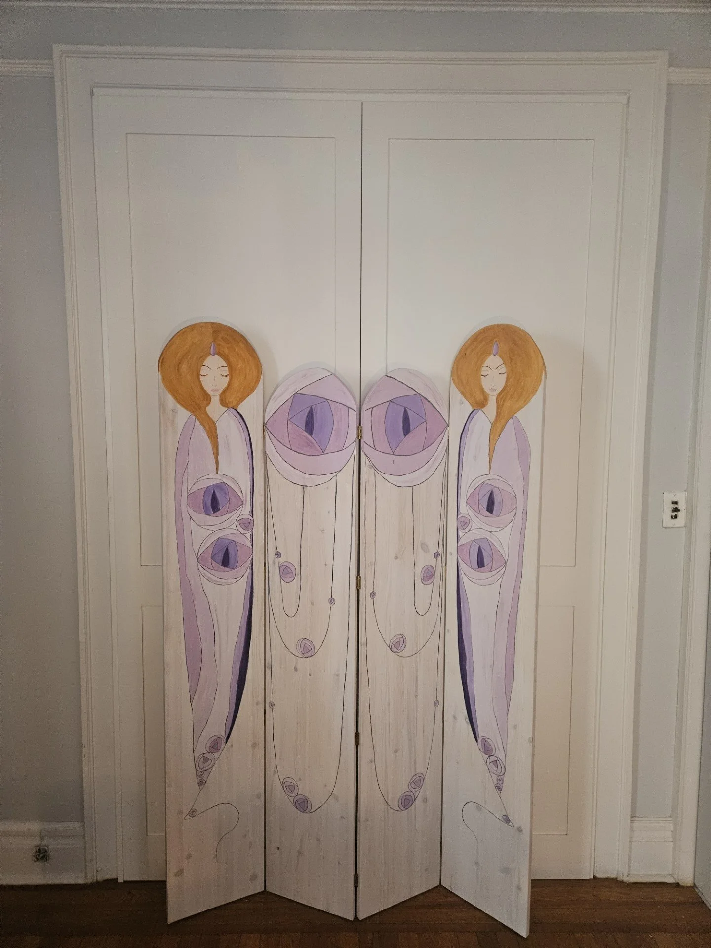 Decorative wooden folding screen with artwork of two women with long hair and large eyes, surrounded by abstract organic shapes in pastel colors.