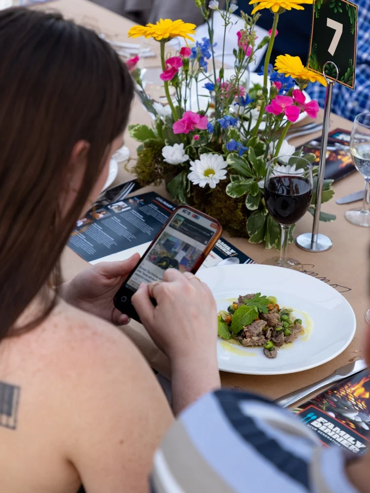Person looking at KCUR website on her smartphone while at a KCUR event with flowers on the table