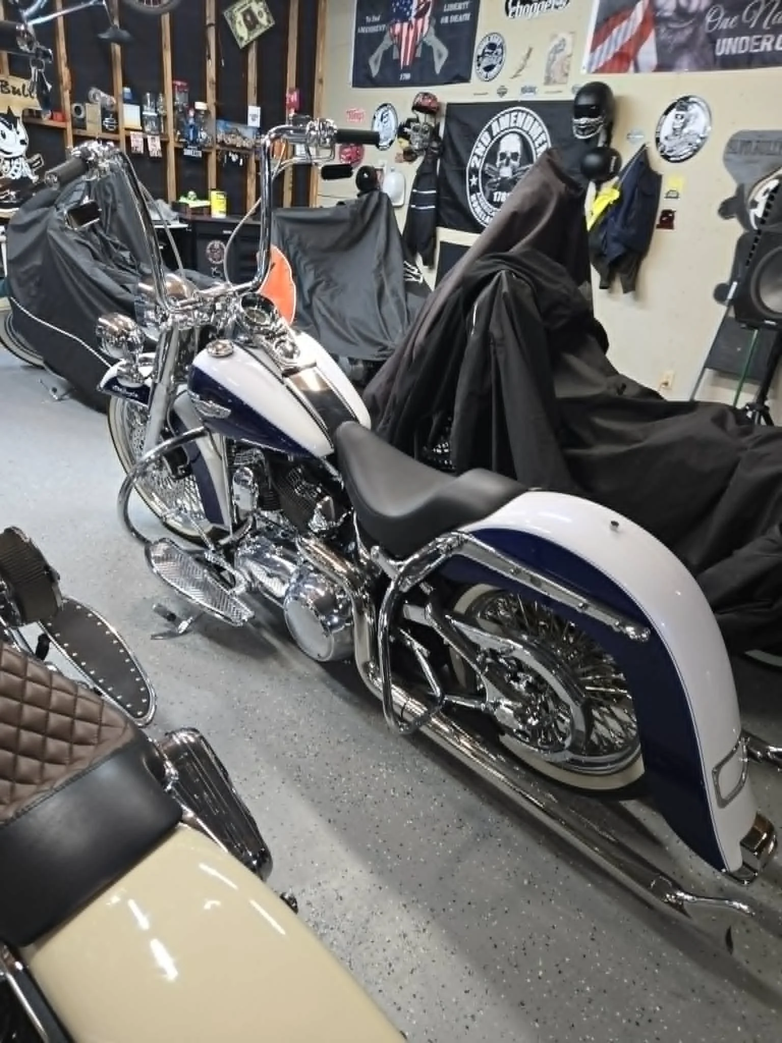 Various motorcycles parked in a garage with Harley-Davidson memorabilia and posters on the walls.