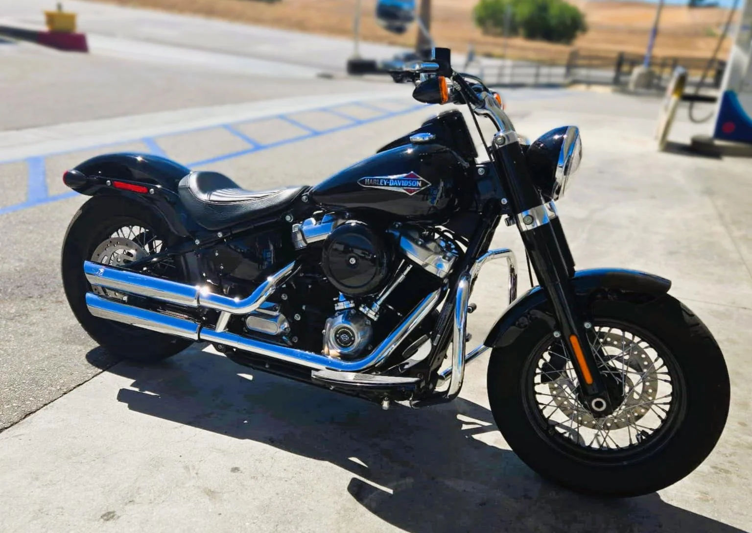 A black Harley-Davidson motorcycle parked in a concrete lot with a blue sky background.