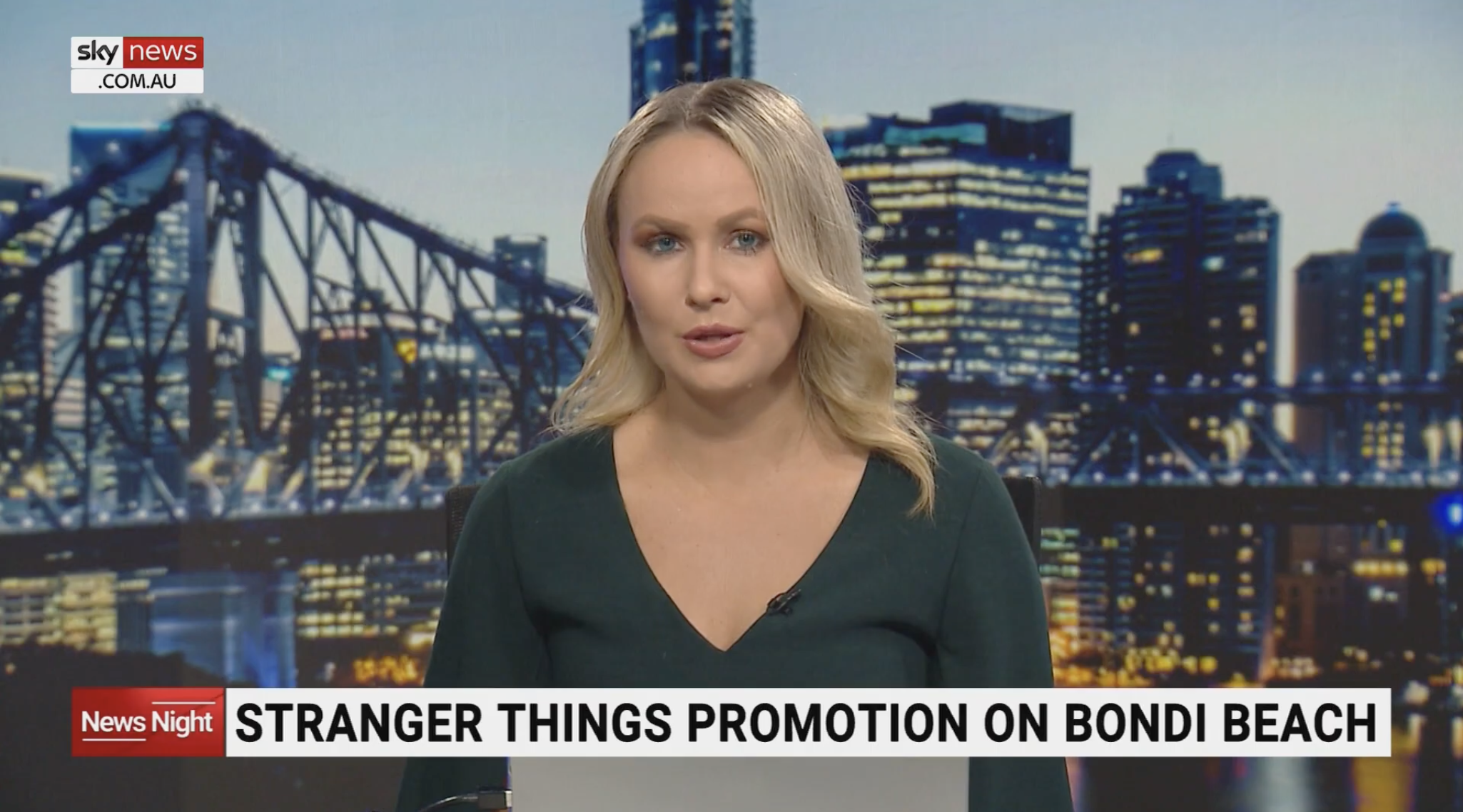 Female news anchor in a studio with a cityscape background, reporting a story about a strange promotion on Bondi Beach, with a 'Sky News' logo on the screen.
