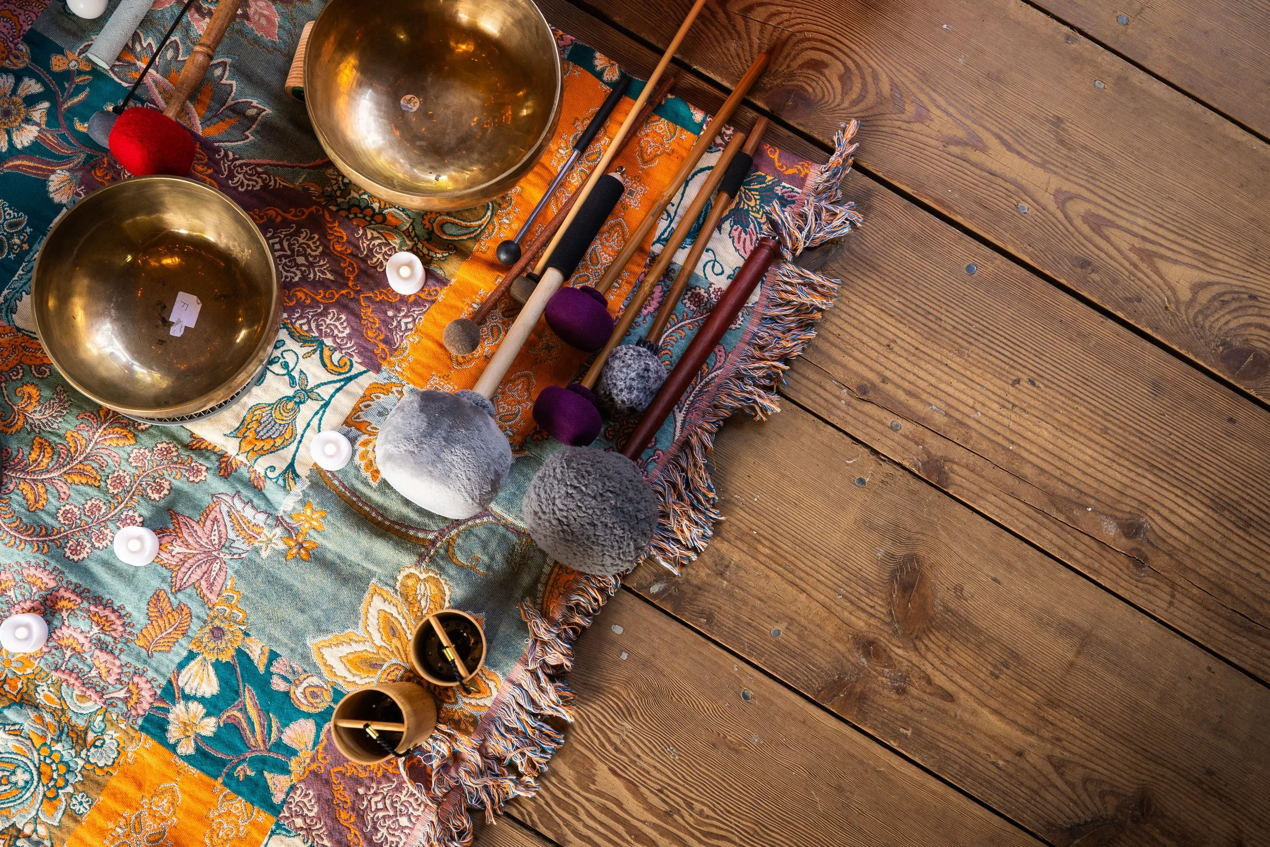 Sound bowls with gong instruments sitting on a patchwork quilt.