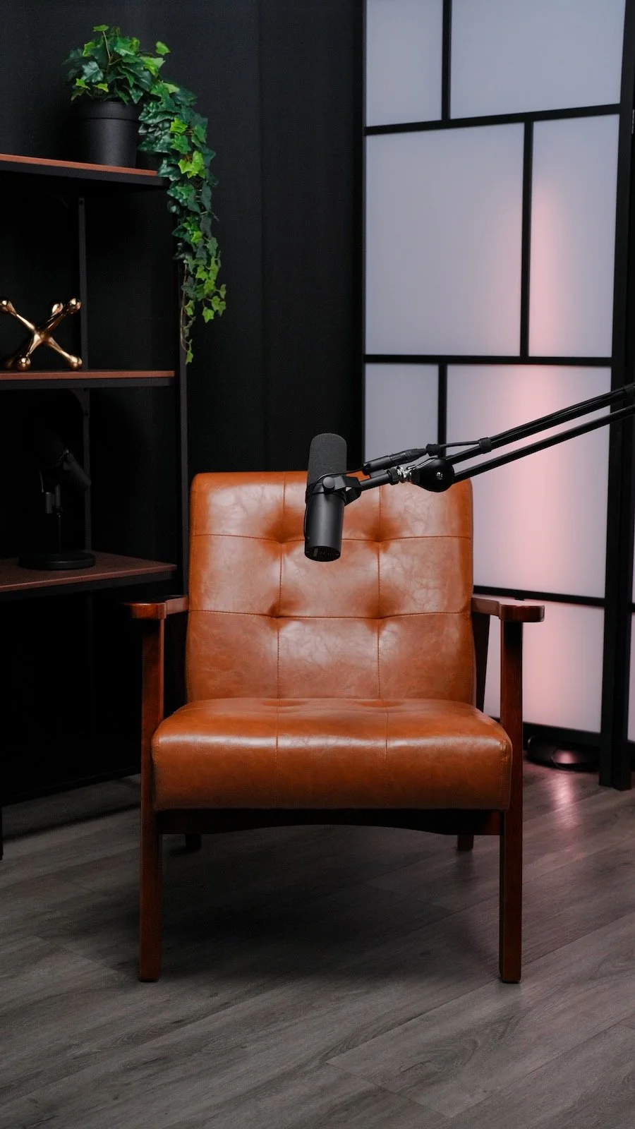 Podcast recording setup with a leather chair and studio mic at Noble Frequency.