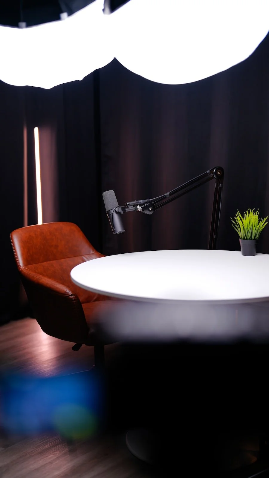 Podcast set design at Noble Frequency studio in Temecula–Murrieta — leather chair, table, and mic under studio lighting.