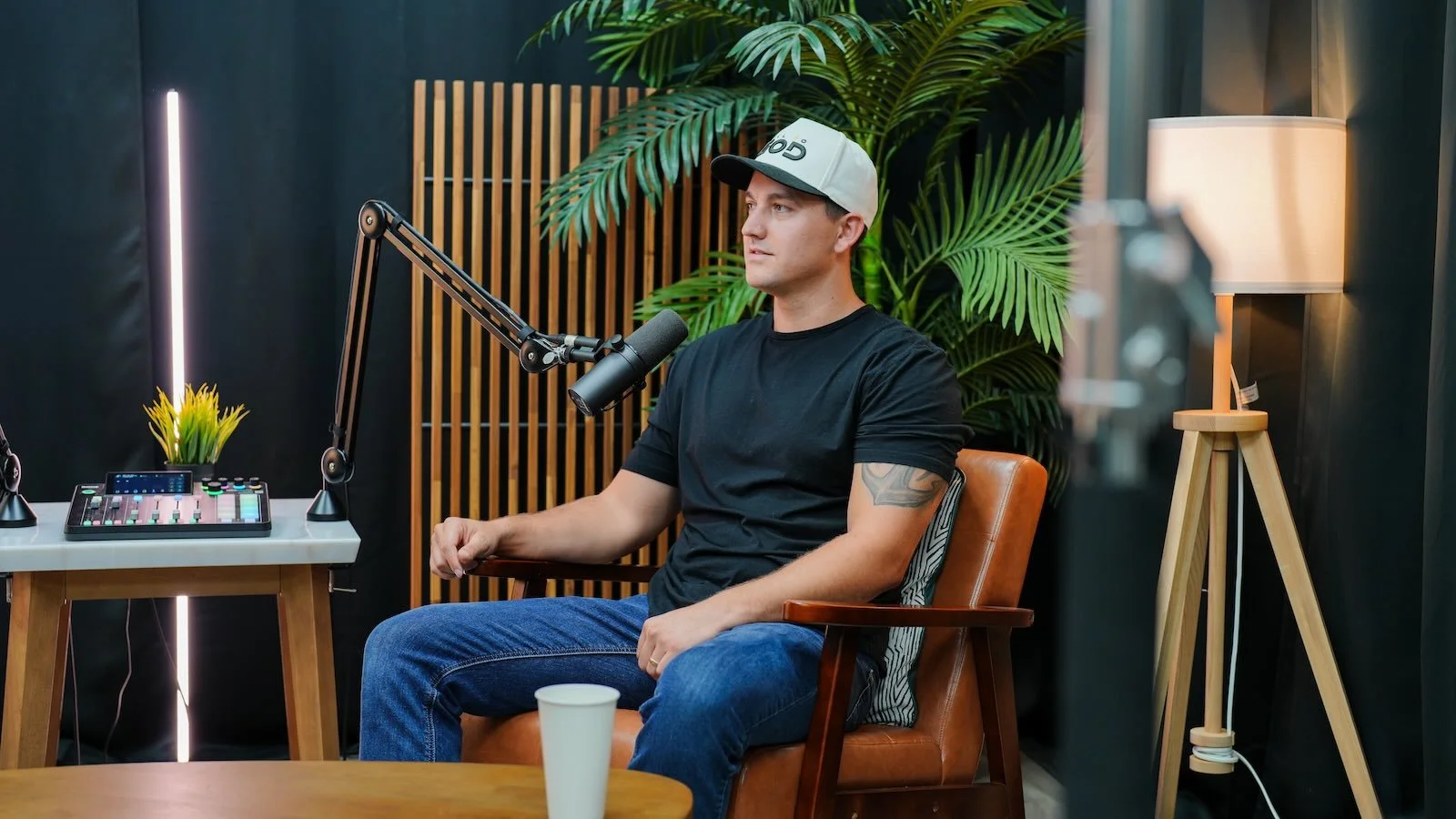 A man recording a podcast in the leather chair at Noble Frequency studio in Temecula–Murrieta, with mixing board and mic in frame.