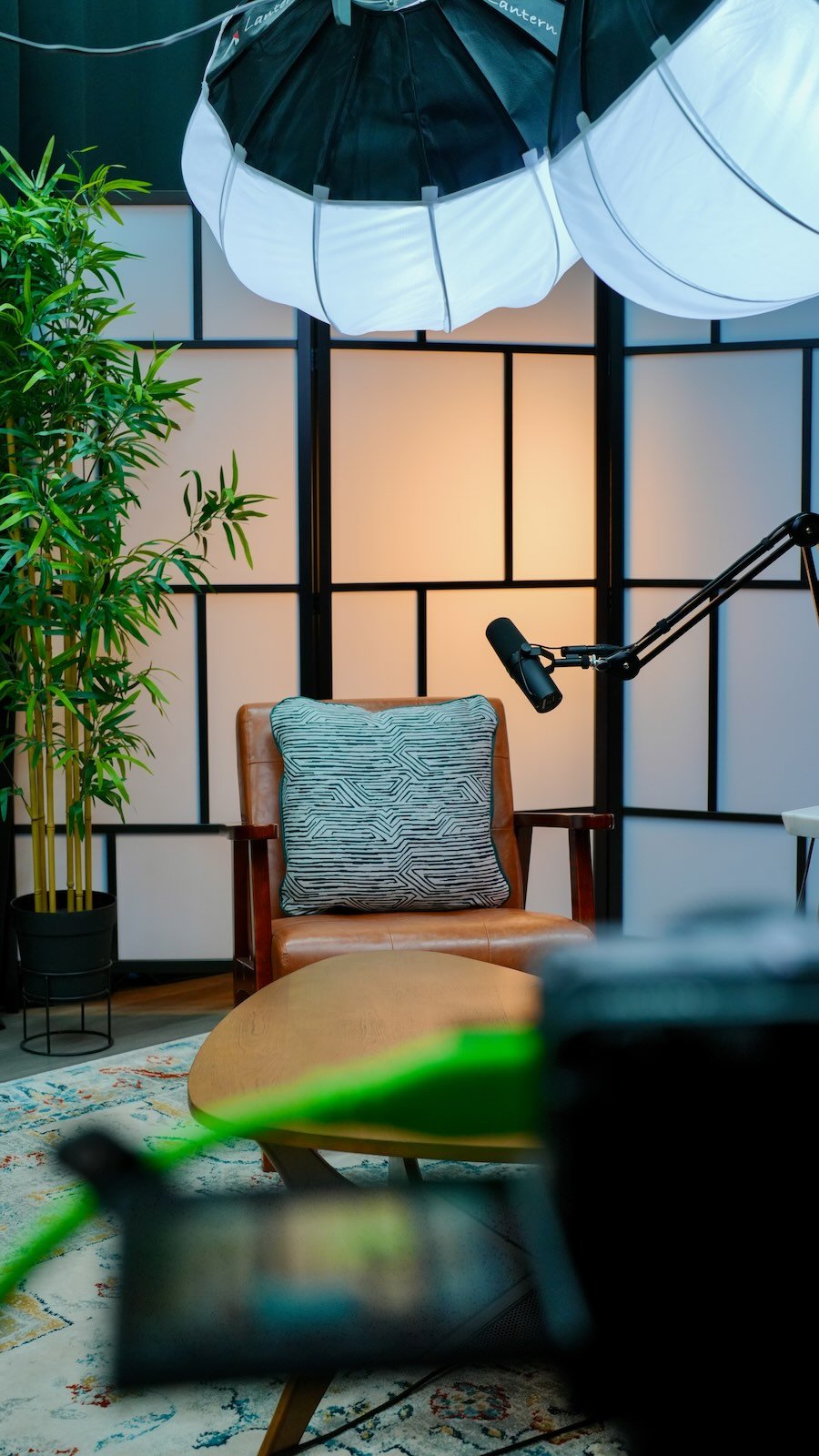 Podcast studio set with leather chair, mic, and softbox lighting at Noble Frequency.