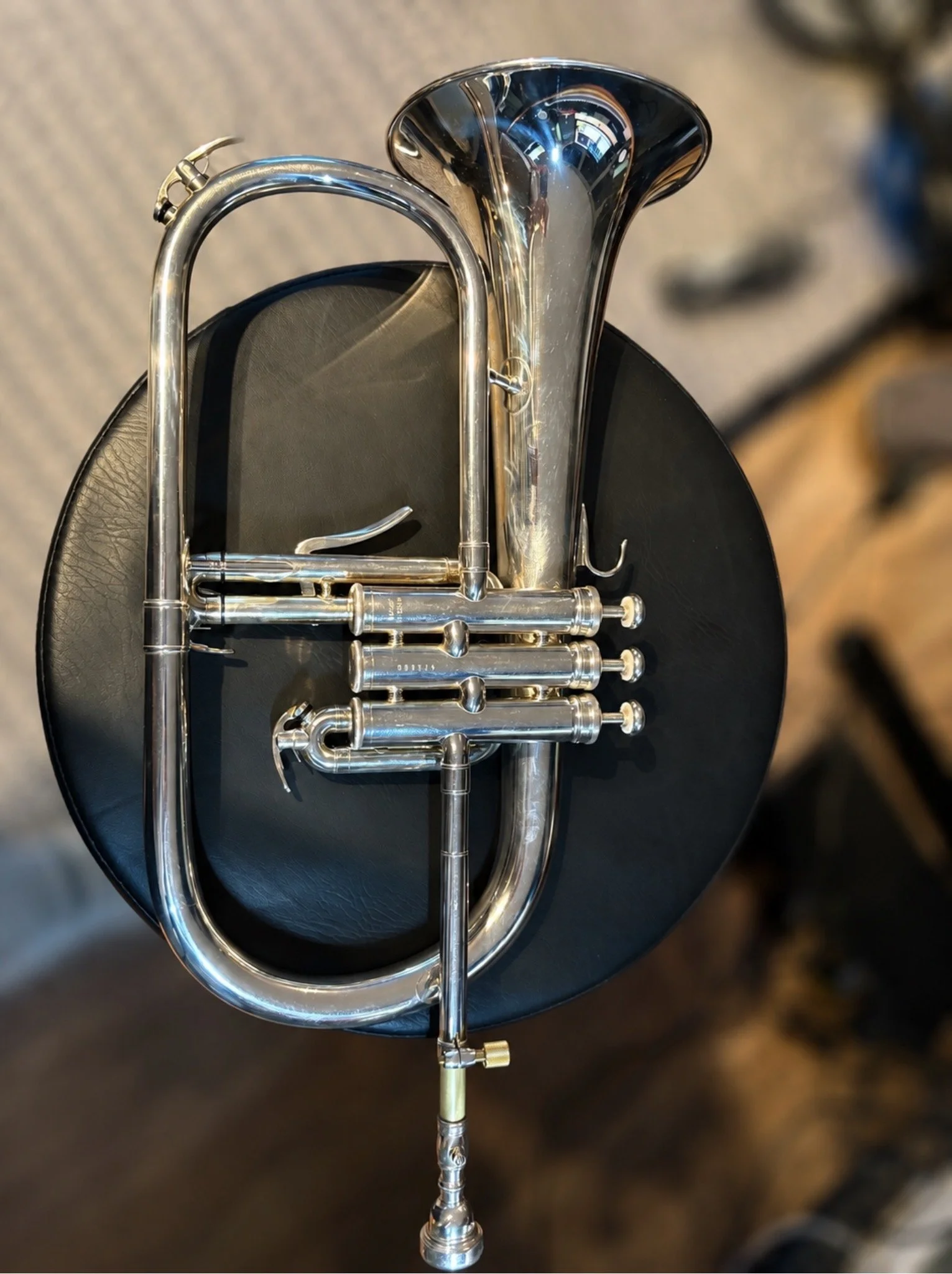 A shiny brass trumpet resting on a black round surface.