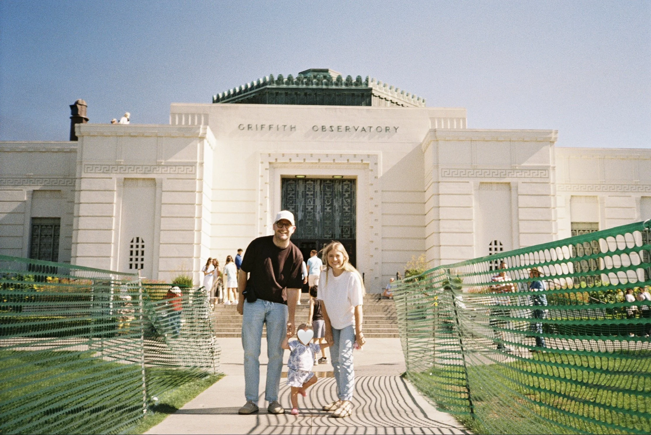 People walking in front of Griffith Observatory on a clear day with a blue sky.