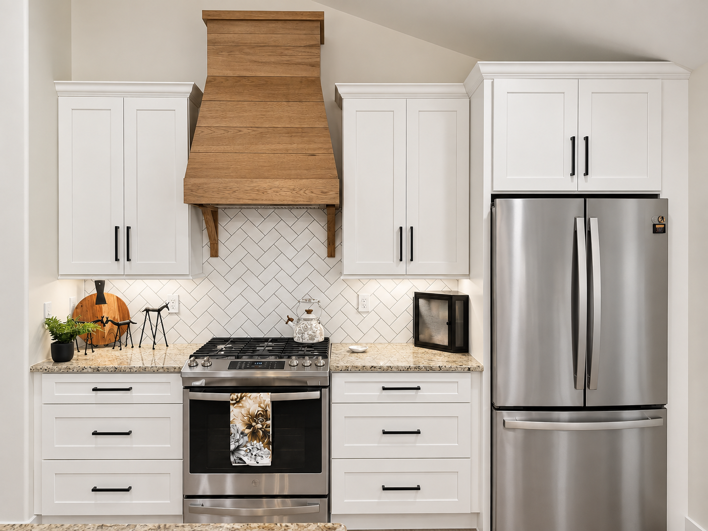 Modern kitchen with white cabinets, stainless steel refrigerator, light countertops, herringbone backsplash, and wooden range hood.
