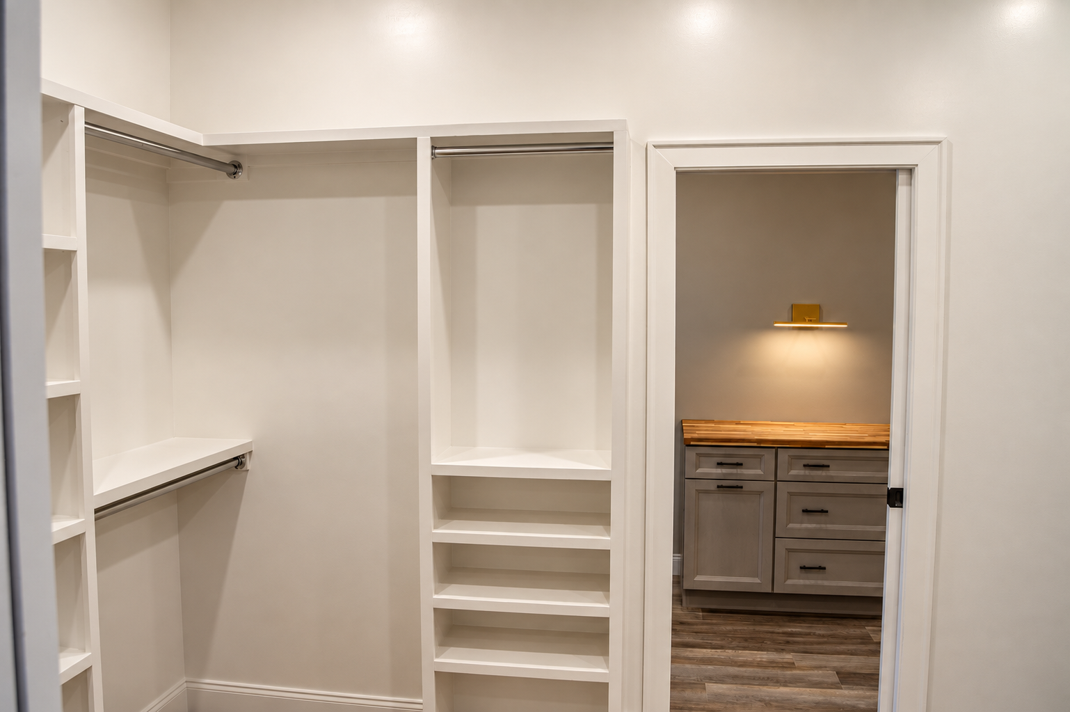 Walk-in closet with white built-in shelves and hanging rods.