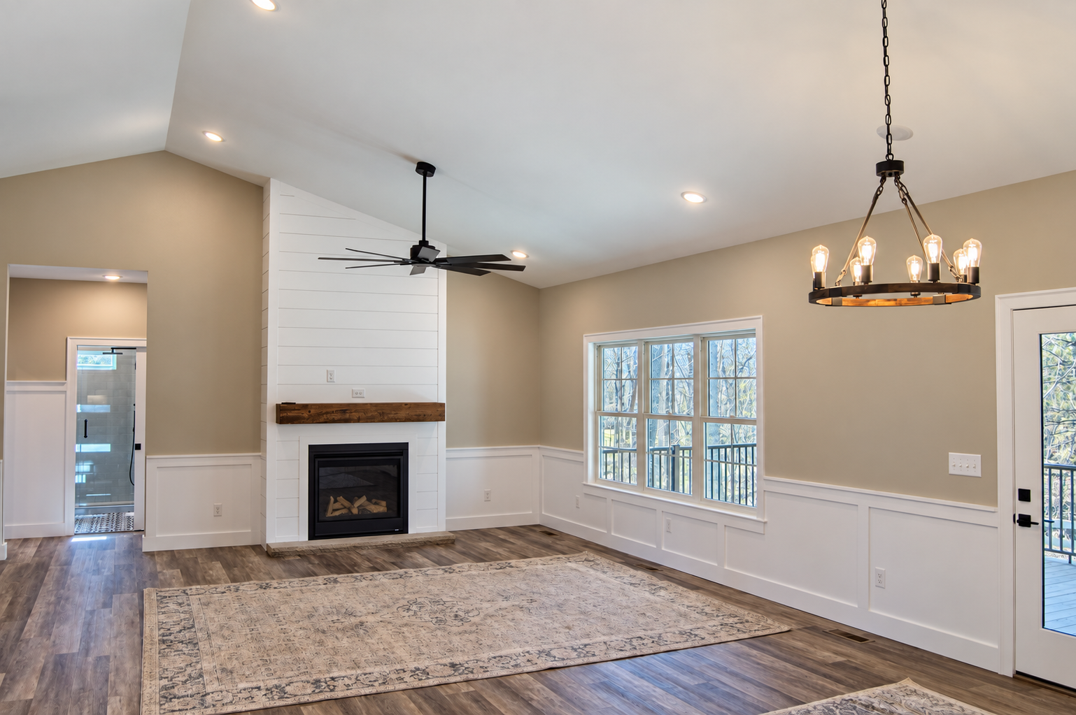 Living room with a fireplace, large windows, and wood floors.