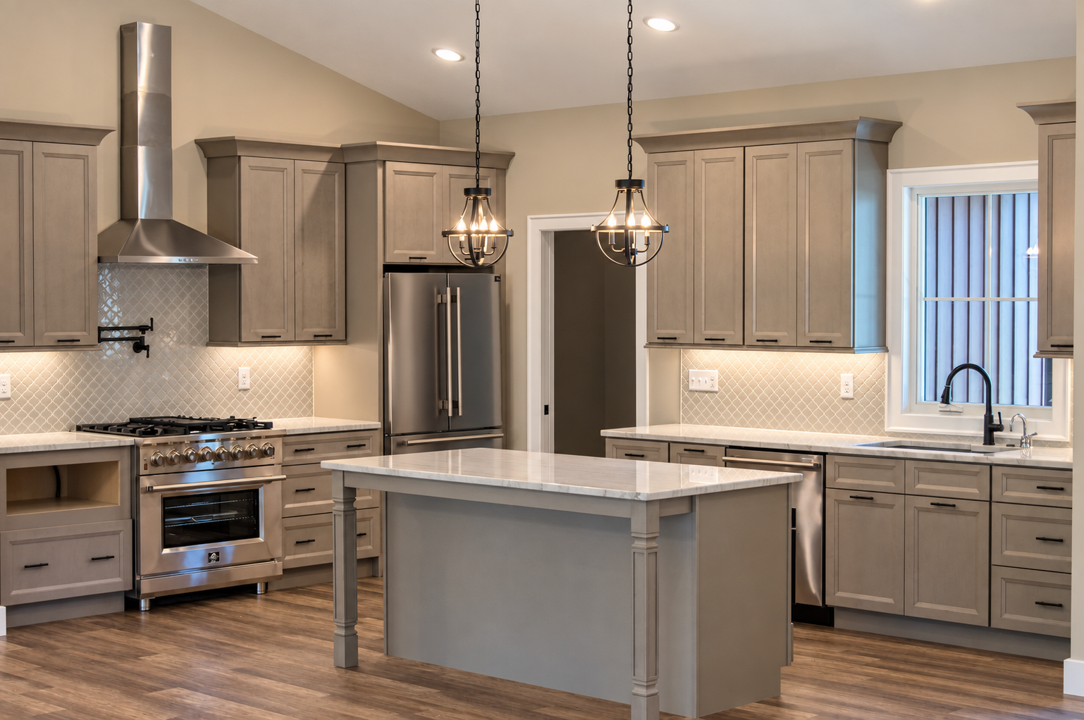 Kitchen with gray cabinets, a central island, stainless steel appliances, and pendant lights. 