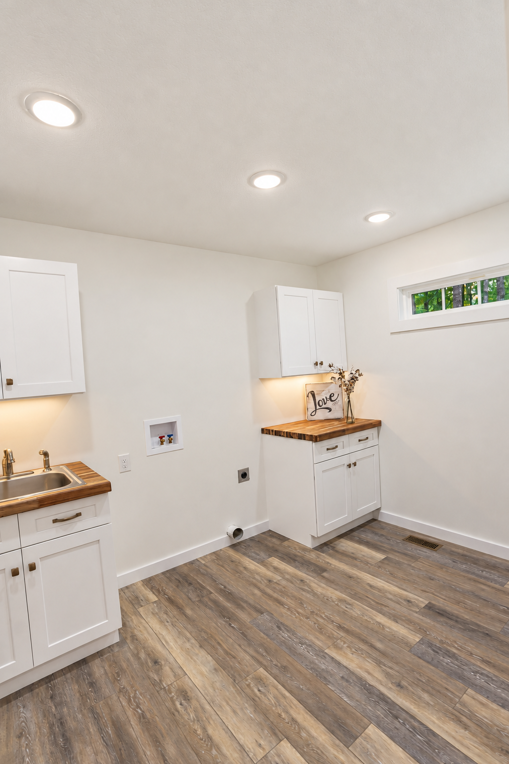 Laundry room with white cabinets, wood countertops, and a window.