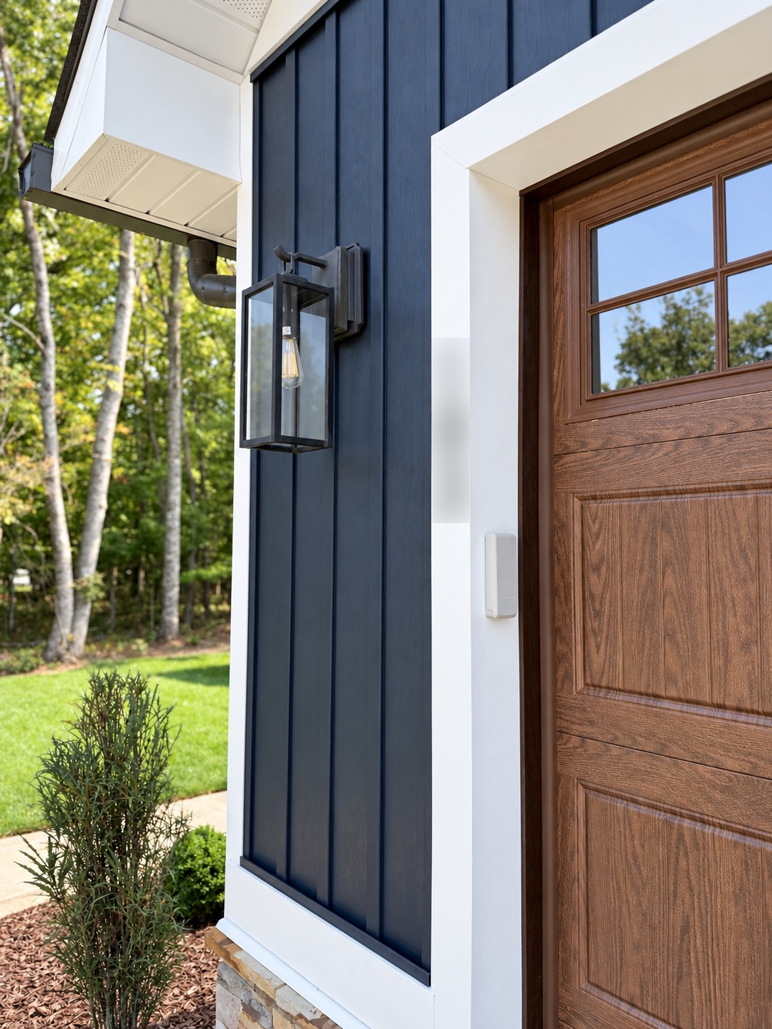 Close-up of a wood garage door, black exterior light, and white trim on a home.