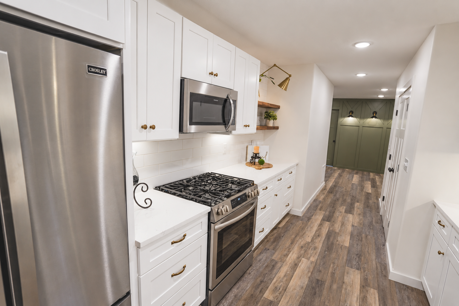 Kitchen with white cabinets, stainless steel appliances, and wood flooring.