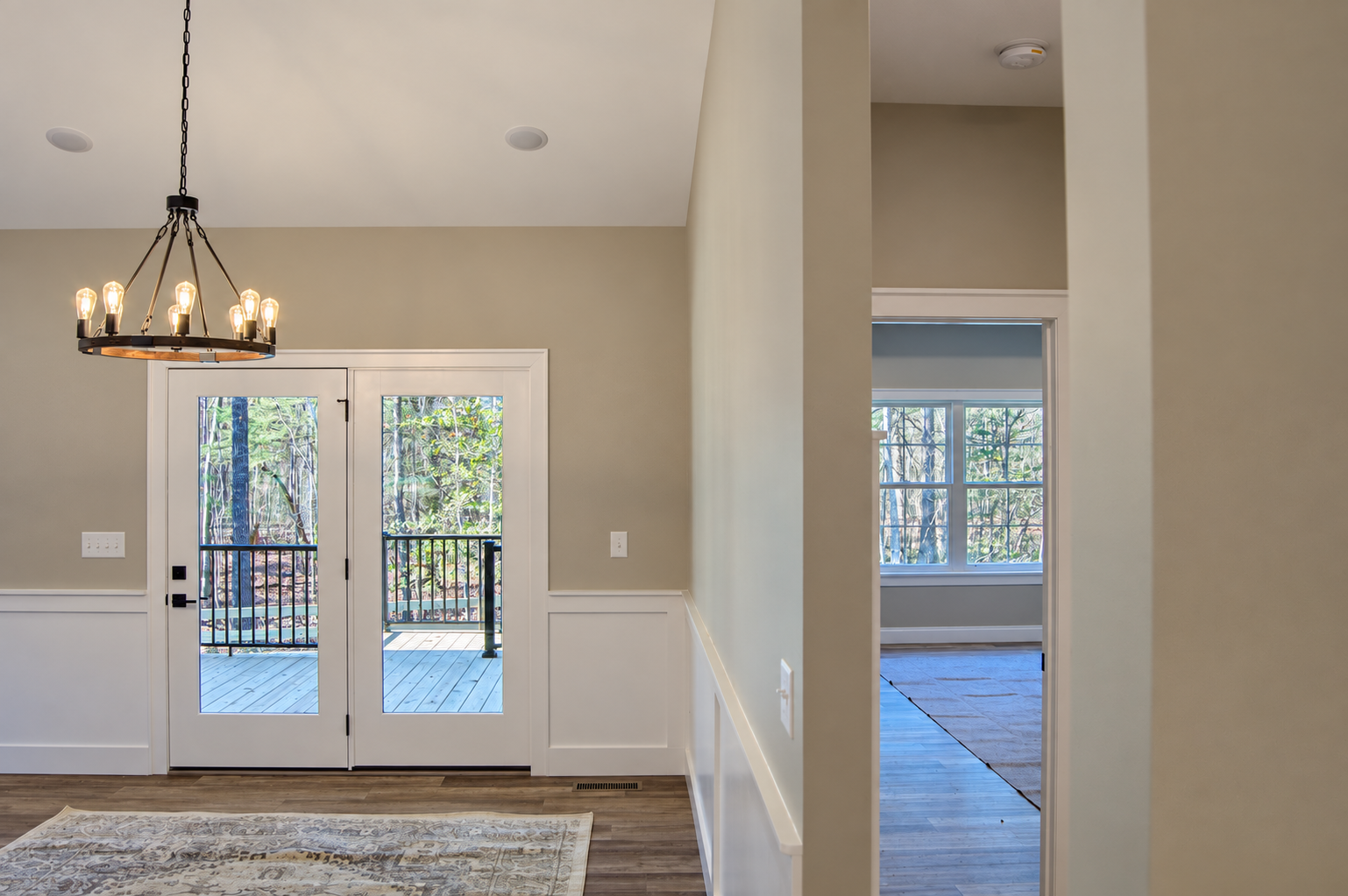 Entry area with glass doors, a chandelier, and a view into the living room.