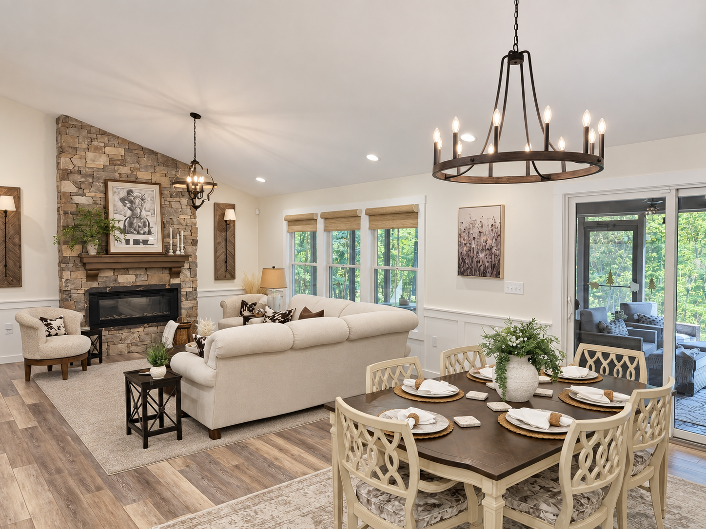 Open living and dining area with a stone fireplace, large windows, and a dark wood dining table.