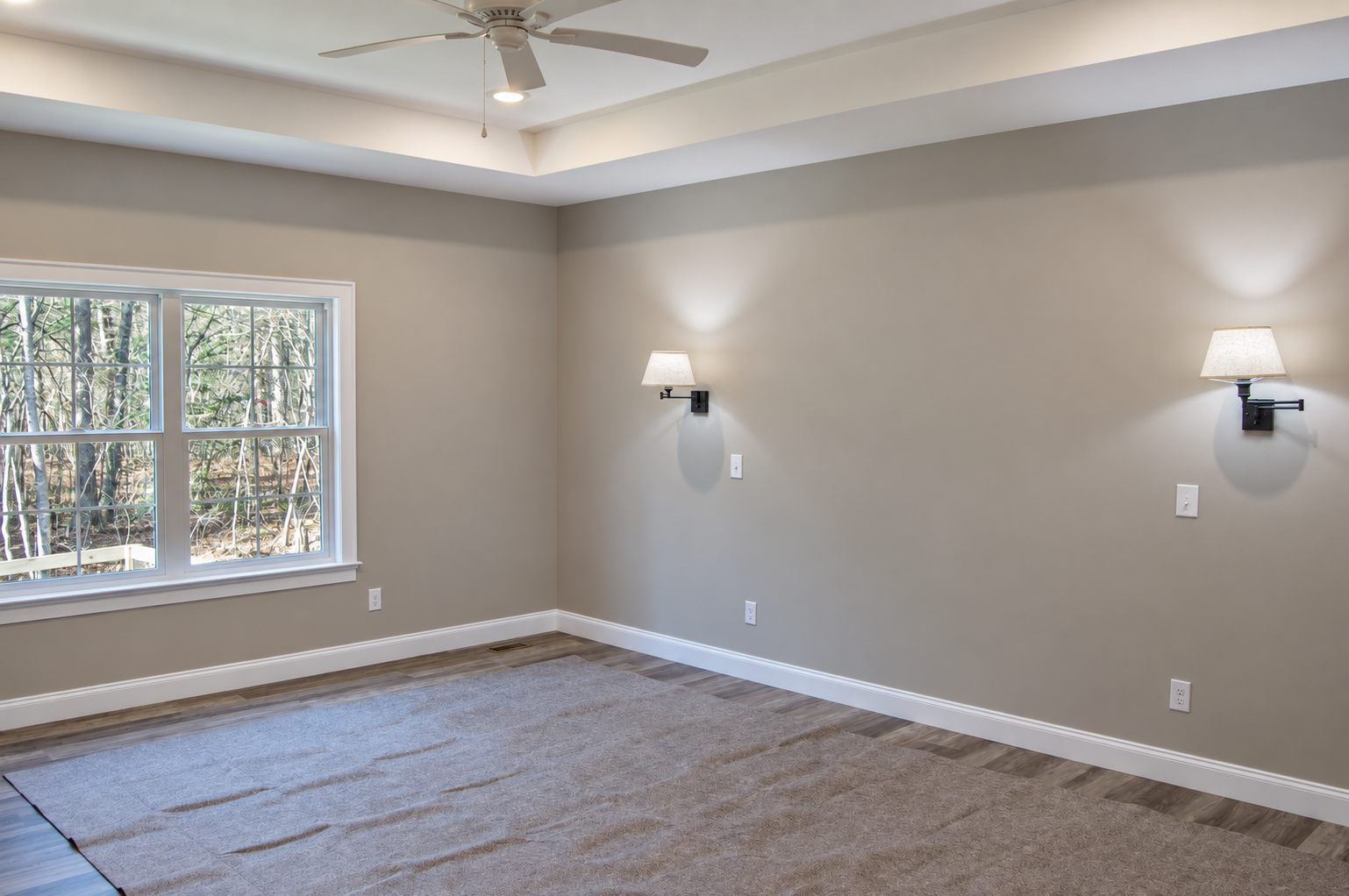 Unfurnished room with beige walls, a large window, and a ceiling fan. 