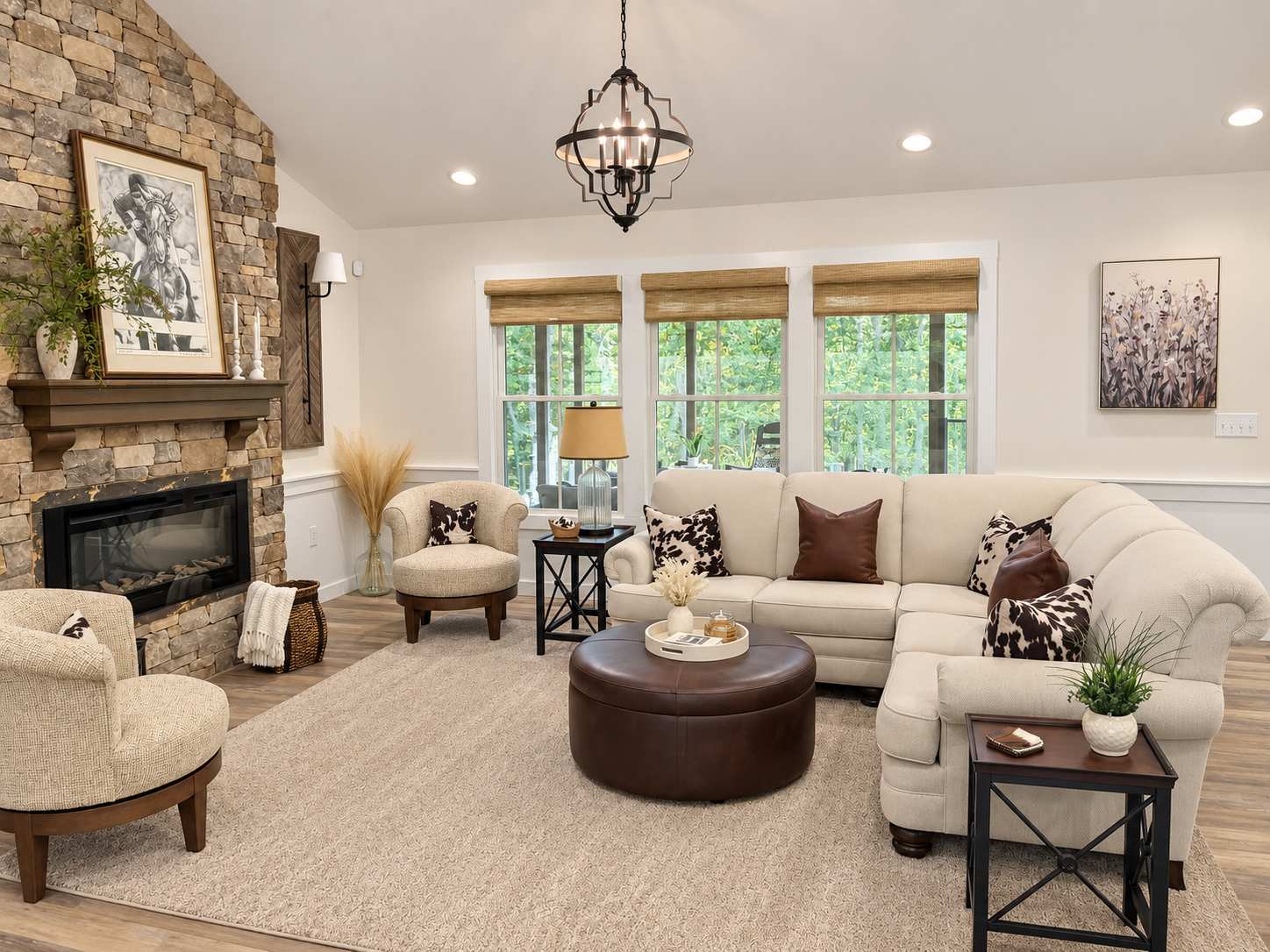 Living room with a sectional, two armchairs, a round ottoman, and a stone fireplace. 