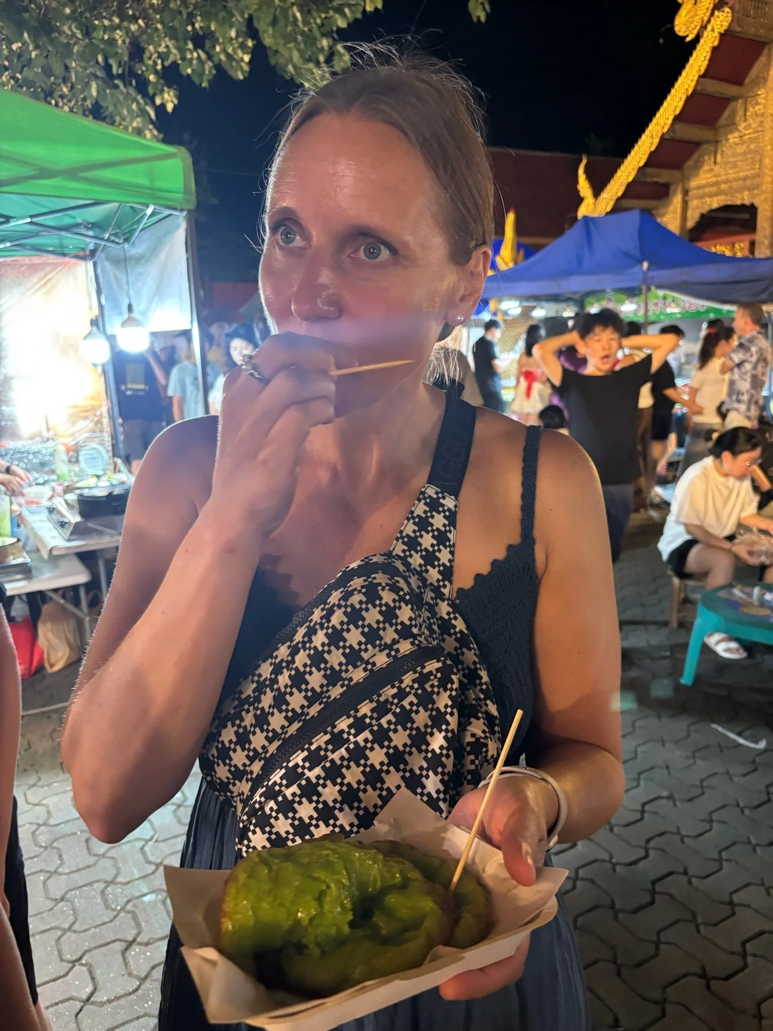 Woman holding a tray of food at an outdoor night market.